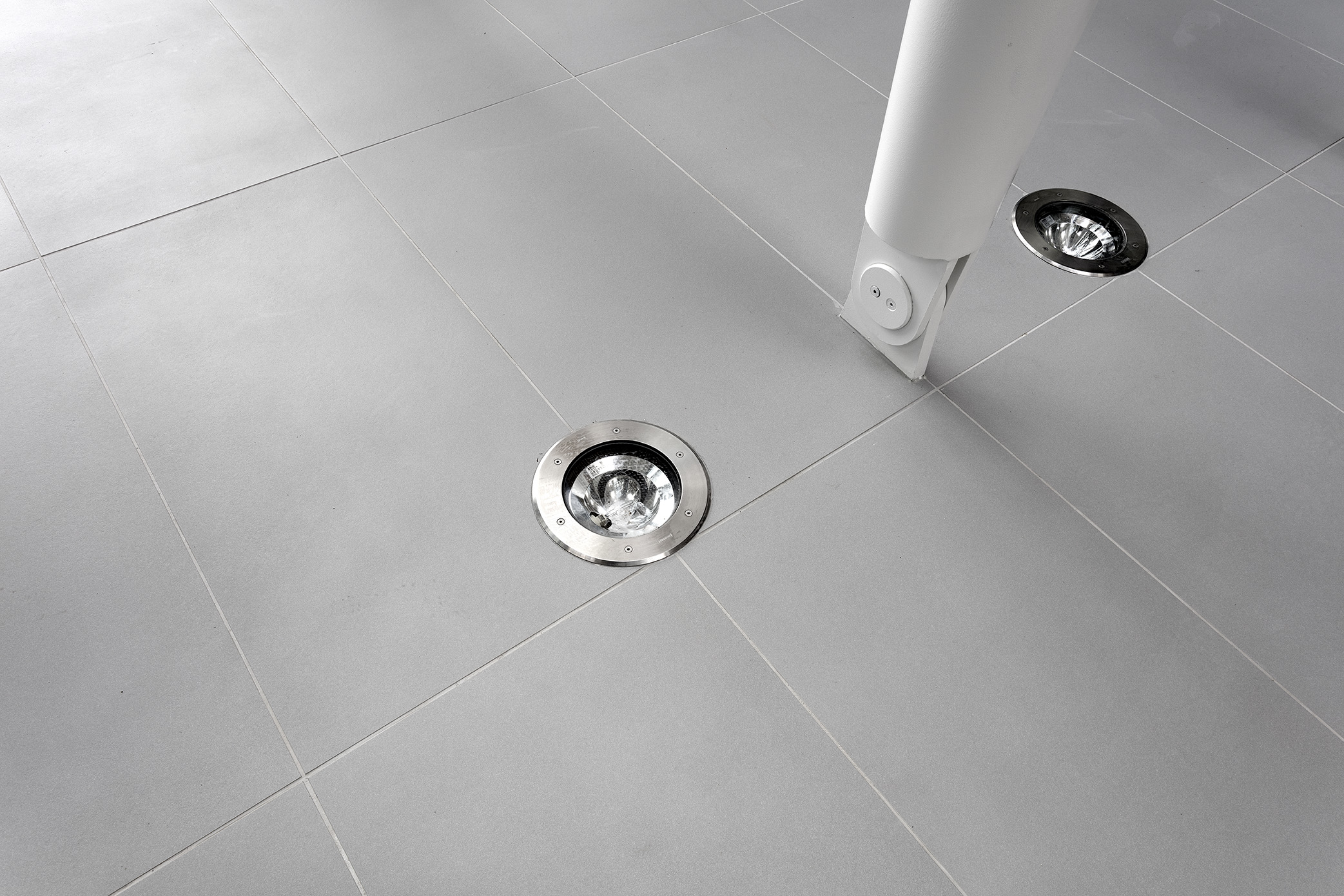 Large-format, light grey tiles with recessed floor spotlights.