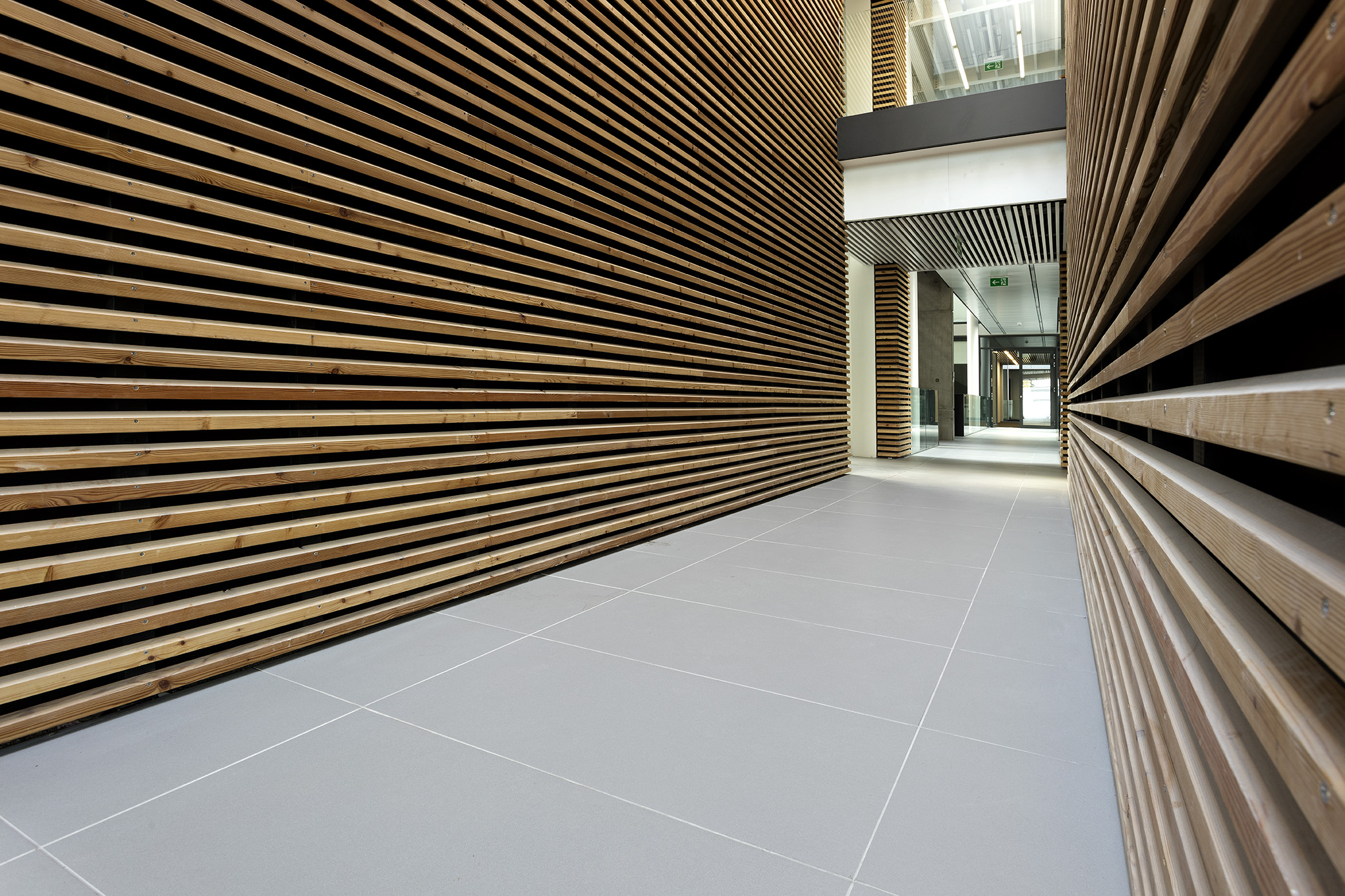 Timeless light grey tile floor with warm wooden slat walls.