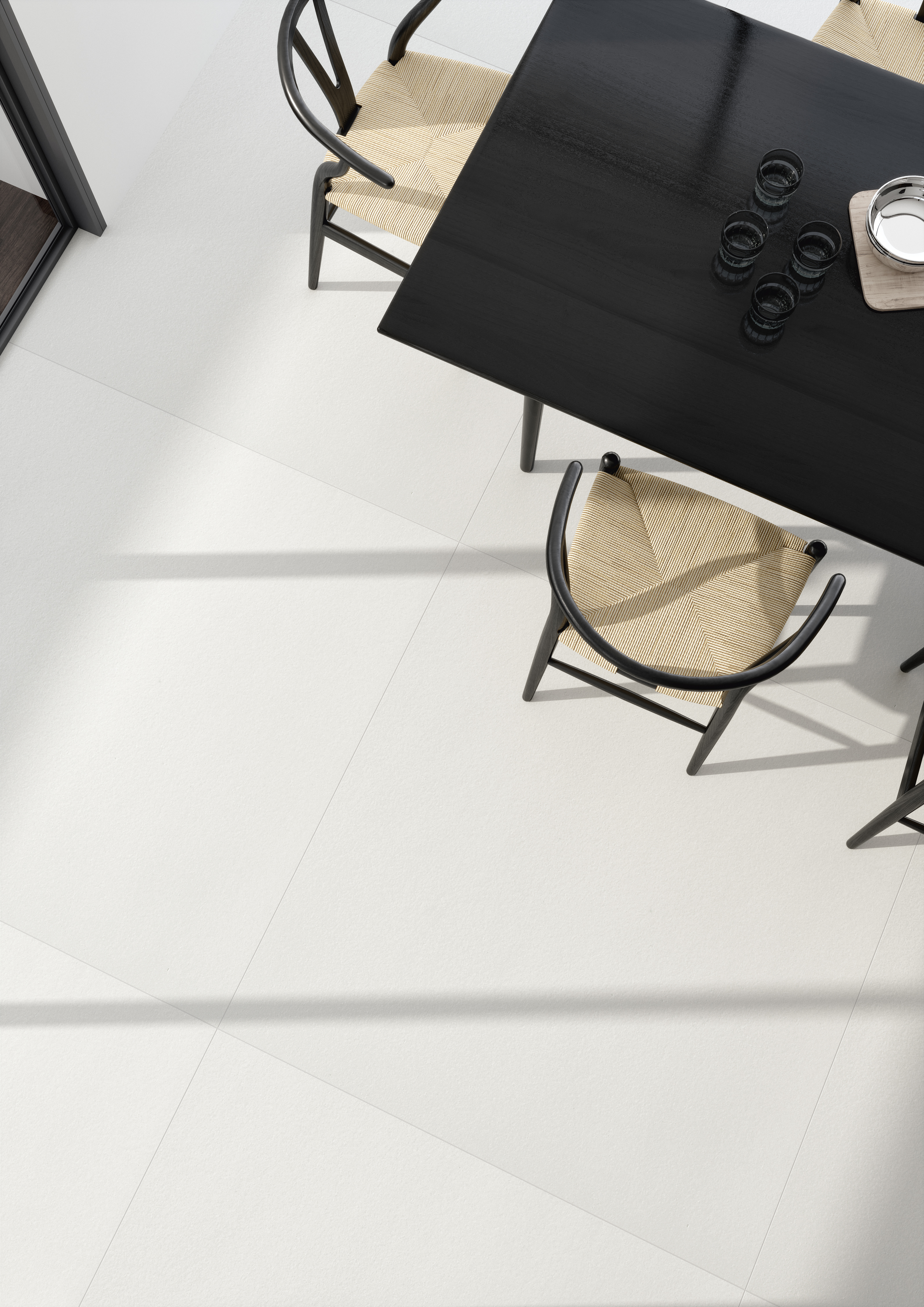 Light, large-format floor tiles in a modern dining area with a dark table.