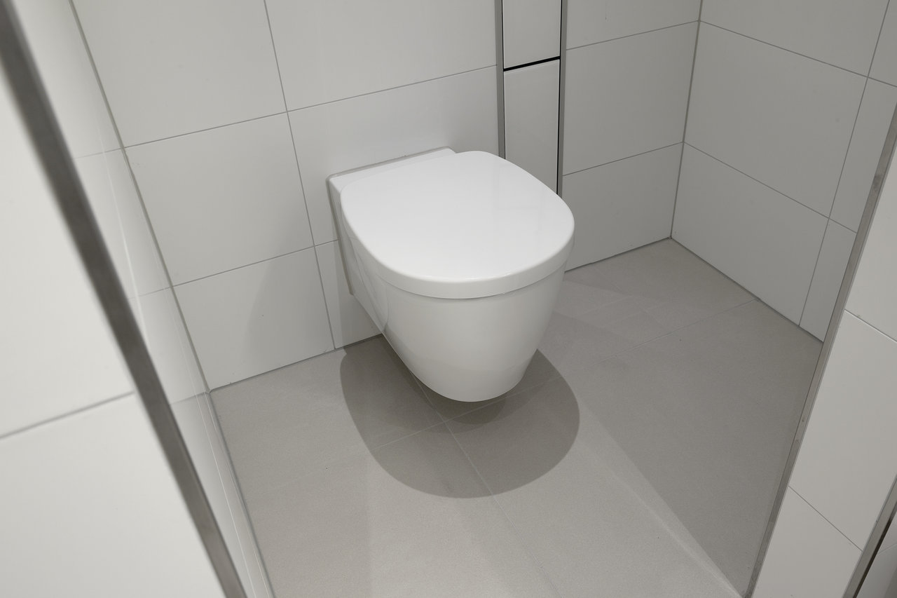 Modern bathroom with white wall tiles and light grey floor tiles.