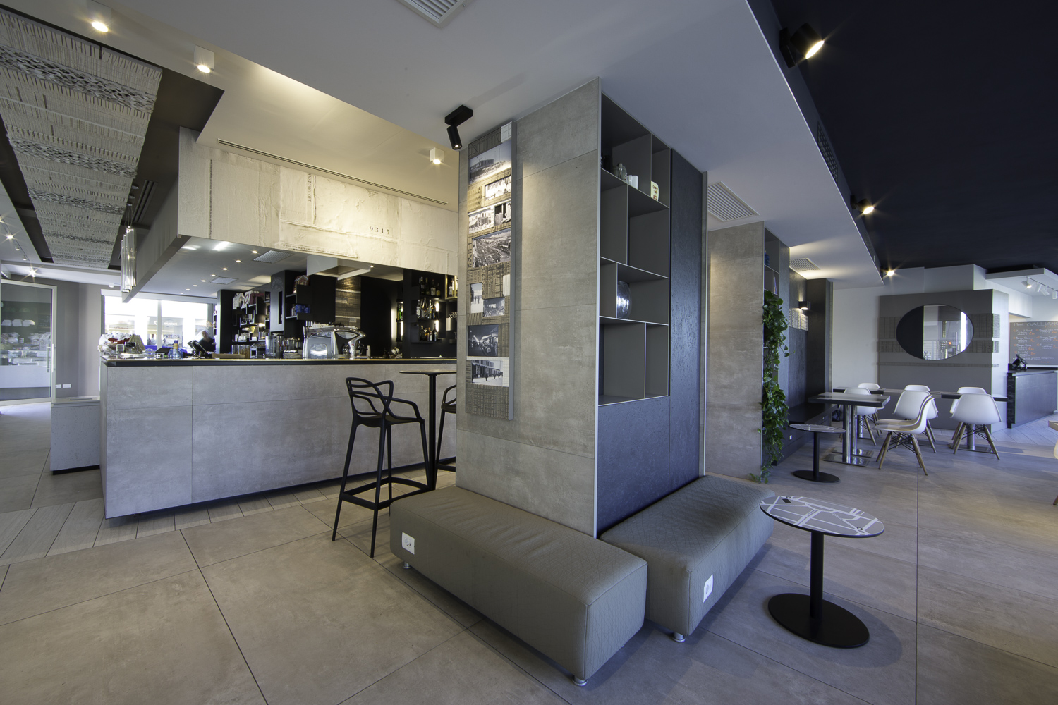 Modern showroom with large-format grey tiles on floor and walls, stylishly decorated.