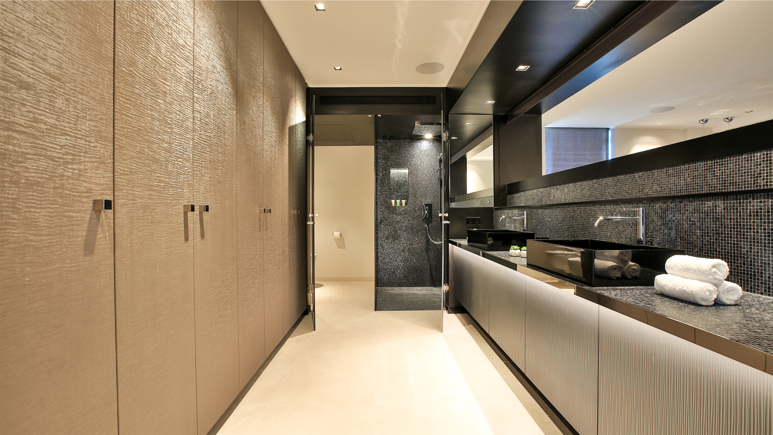 High-quality bathroom design with dark mosaic wall tiles and light floor tiles.