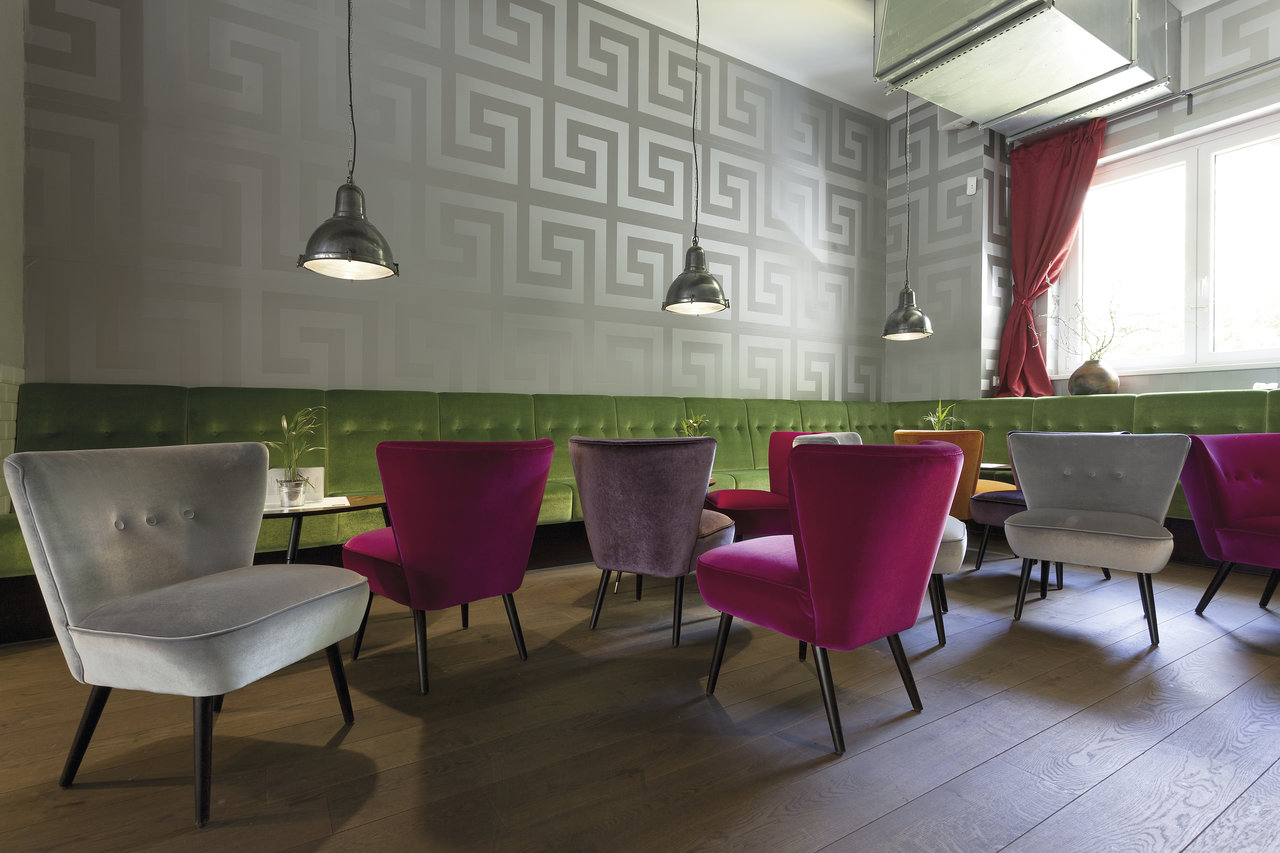 Cozy lounge area with wood-look tiles and colourful armchairs.