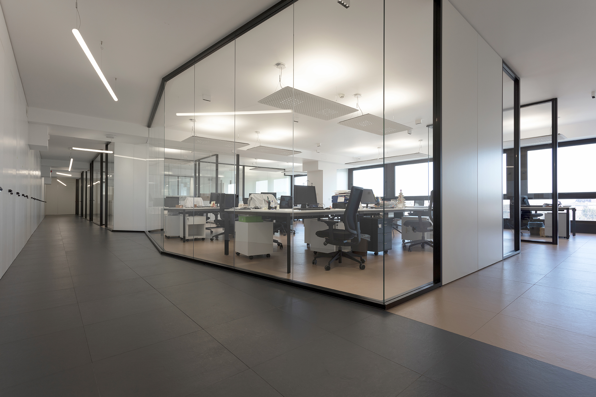 Modern office area with dark floor tiles in the hallway and lighter tiles in the workspace.
