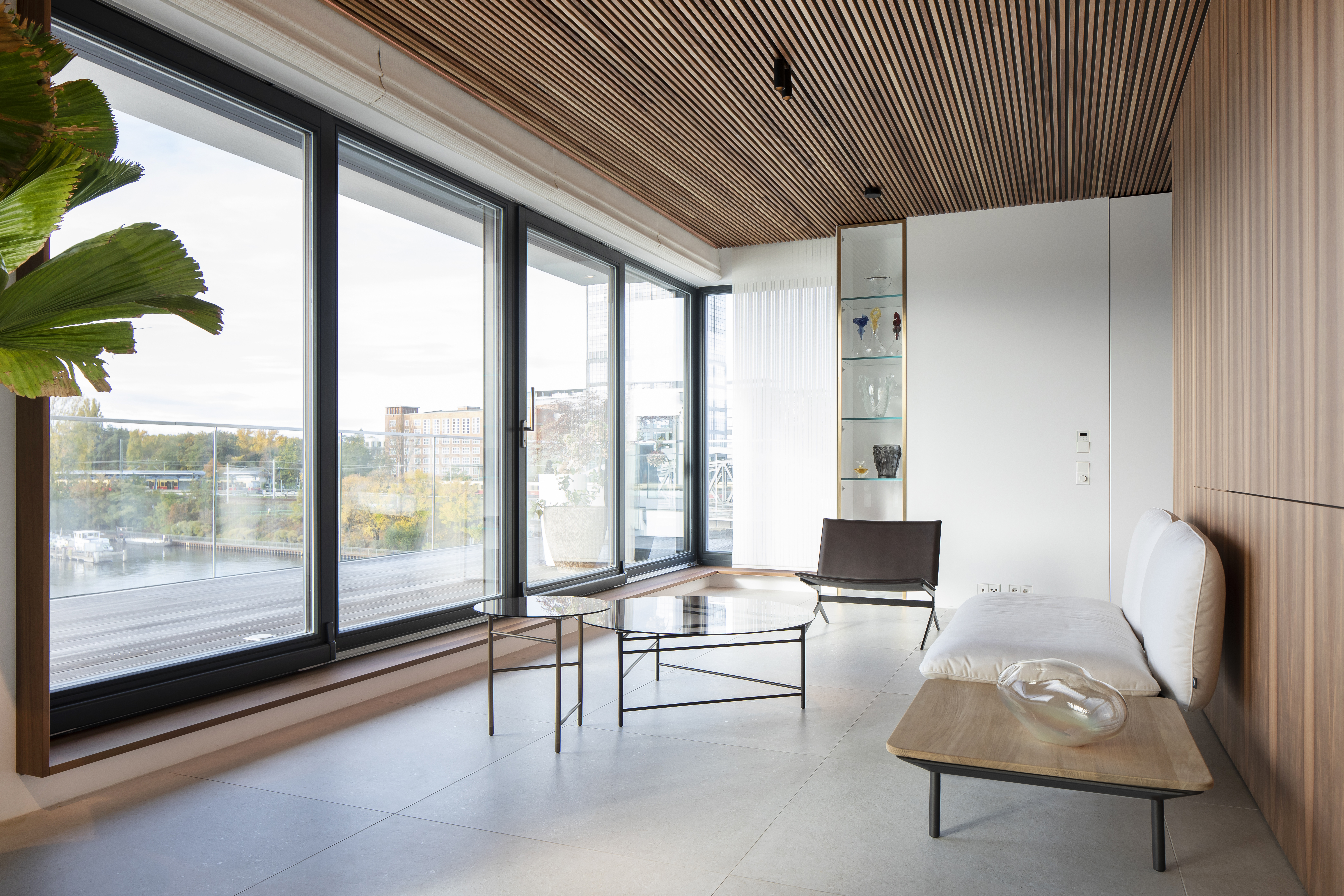 Light, large-format floor tiles in a modern living room with wood accents and natural light.