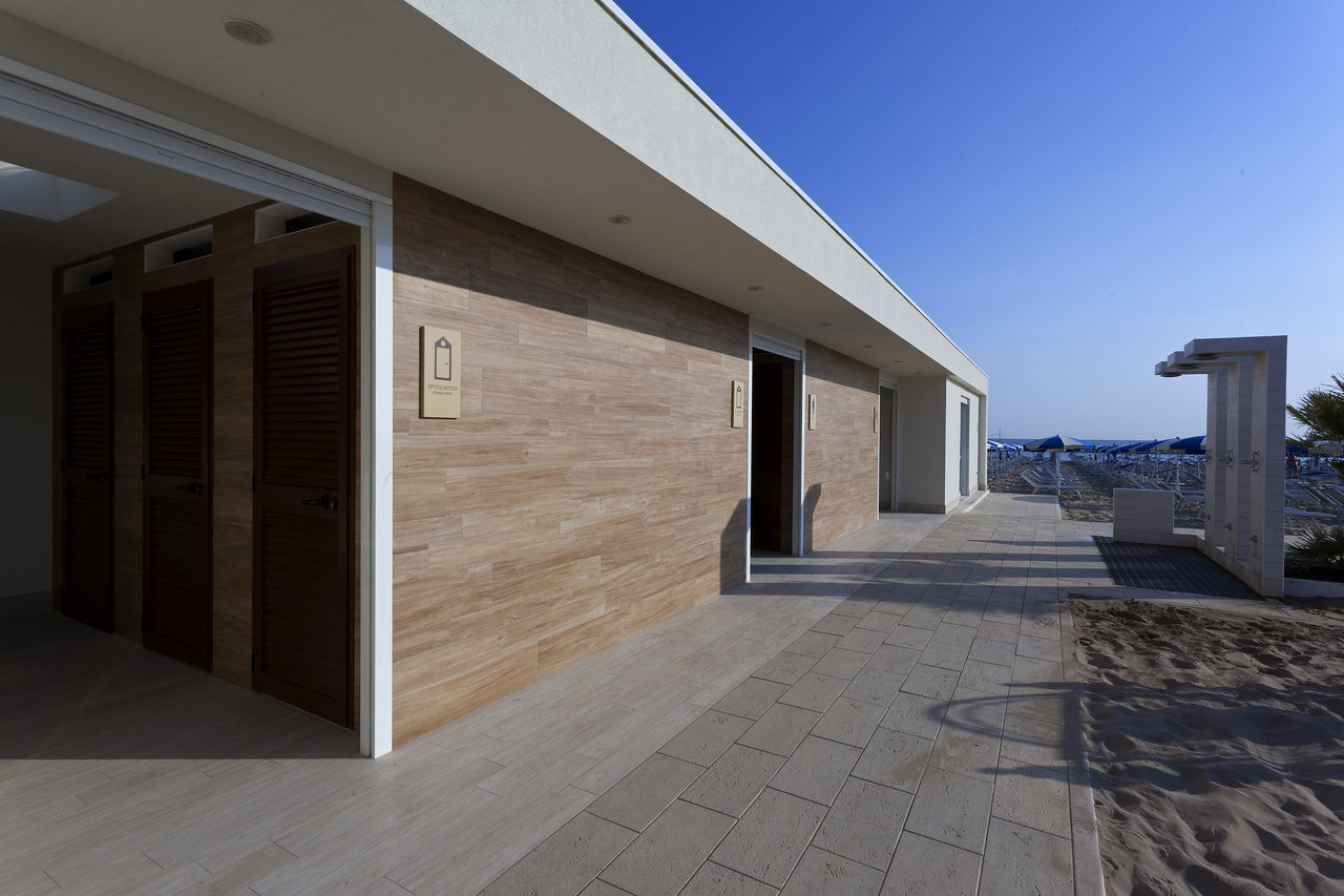 Modern outdoor area with wood-look facade tiles and light floor tiles by the beach.