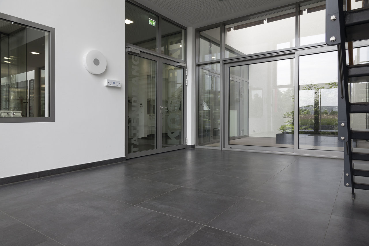 Modern, large-format anthracite tiles in a bright entrance.