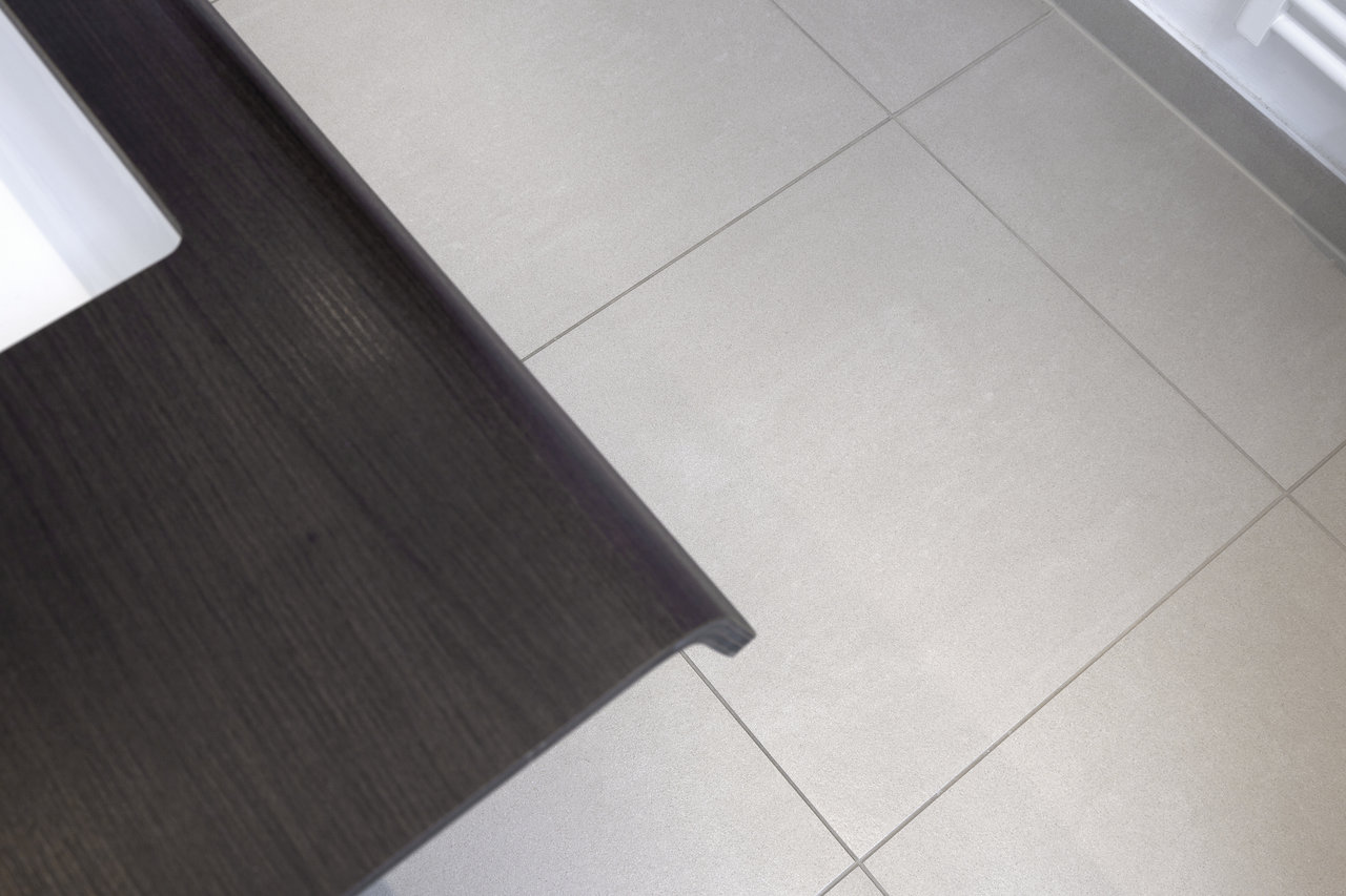 Light, modern floor tiles with fine grout and dark wood effect.