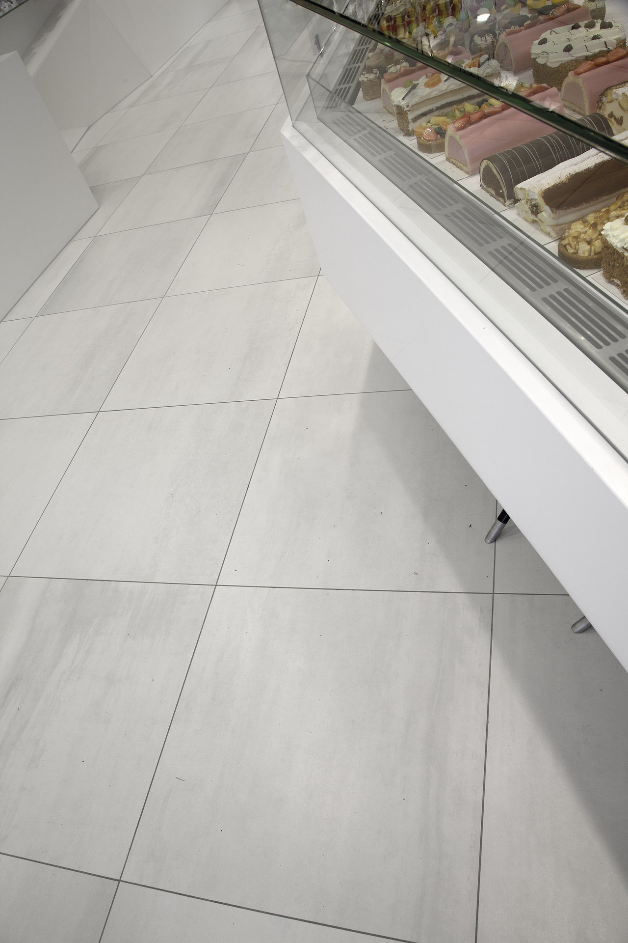Large-format, light porcelain tiles with subtle veining in a café.