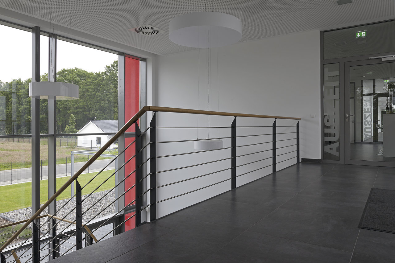 Dark floor tiles in a modern foyer with stairs and access to the showroom.