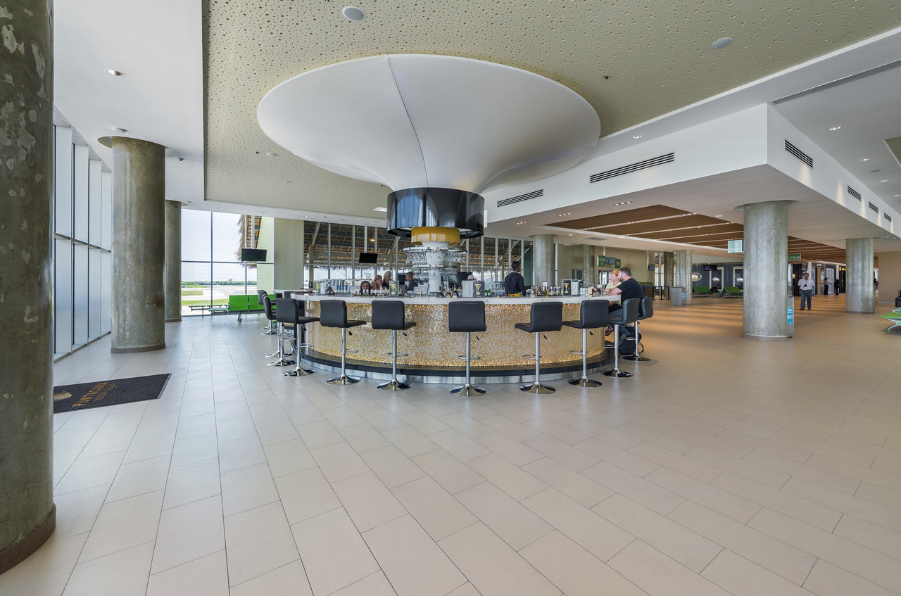 Light, large-format tiles in a modern lounge with a bar.