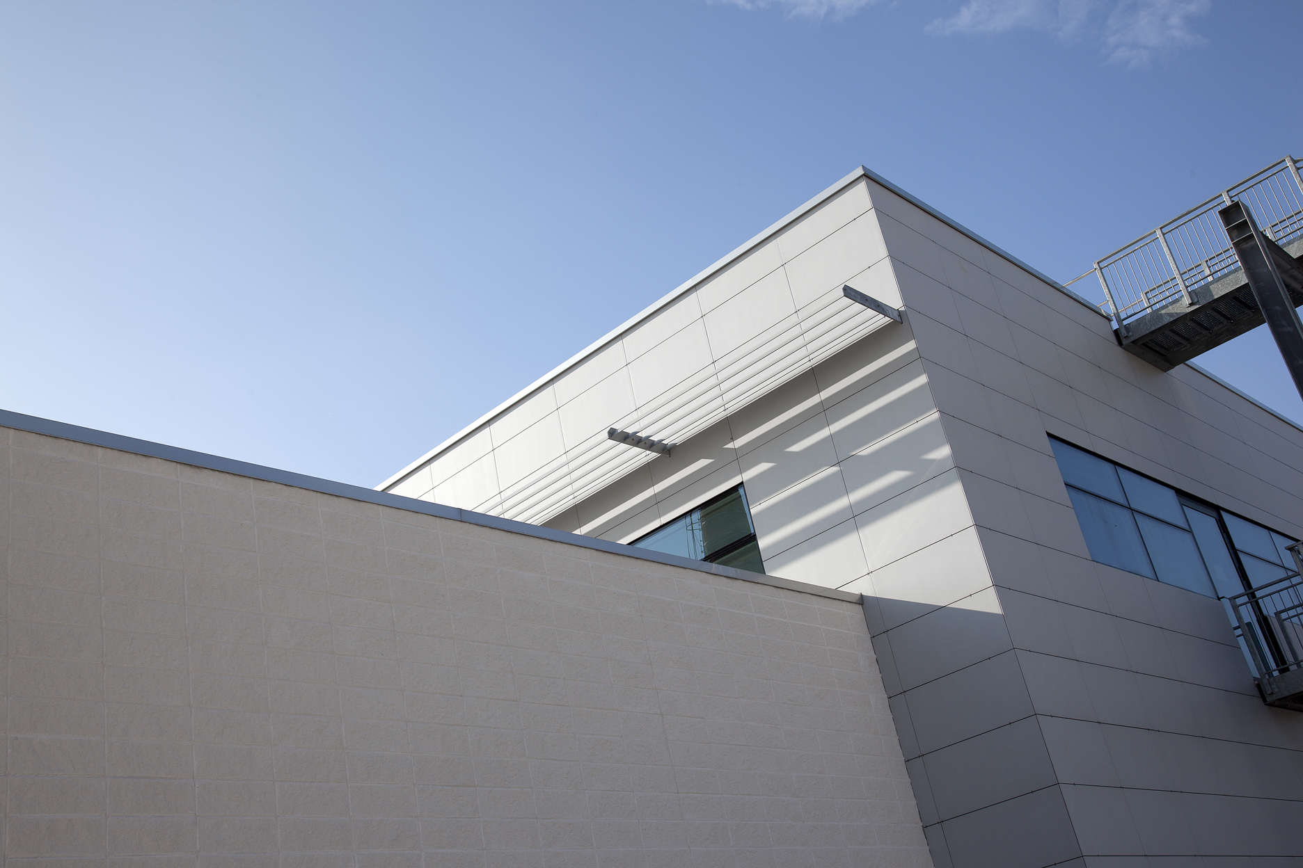 Modern building facade with bright, large-format tiles under a blue sky.