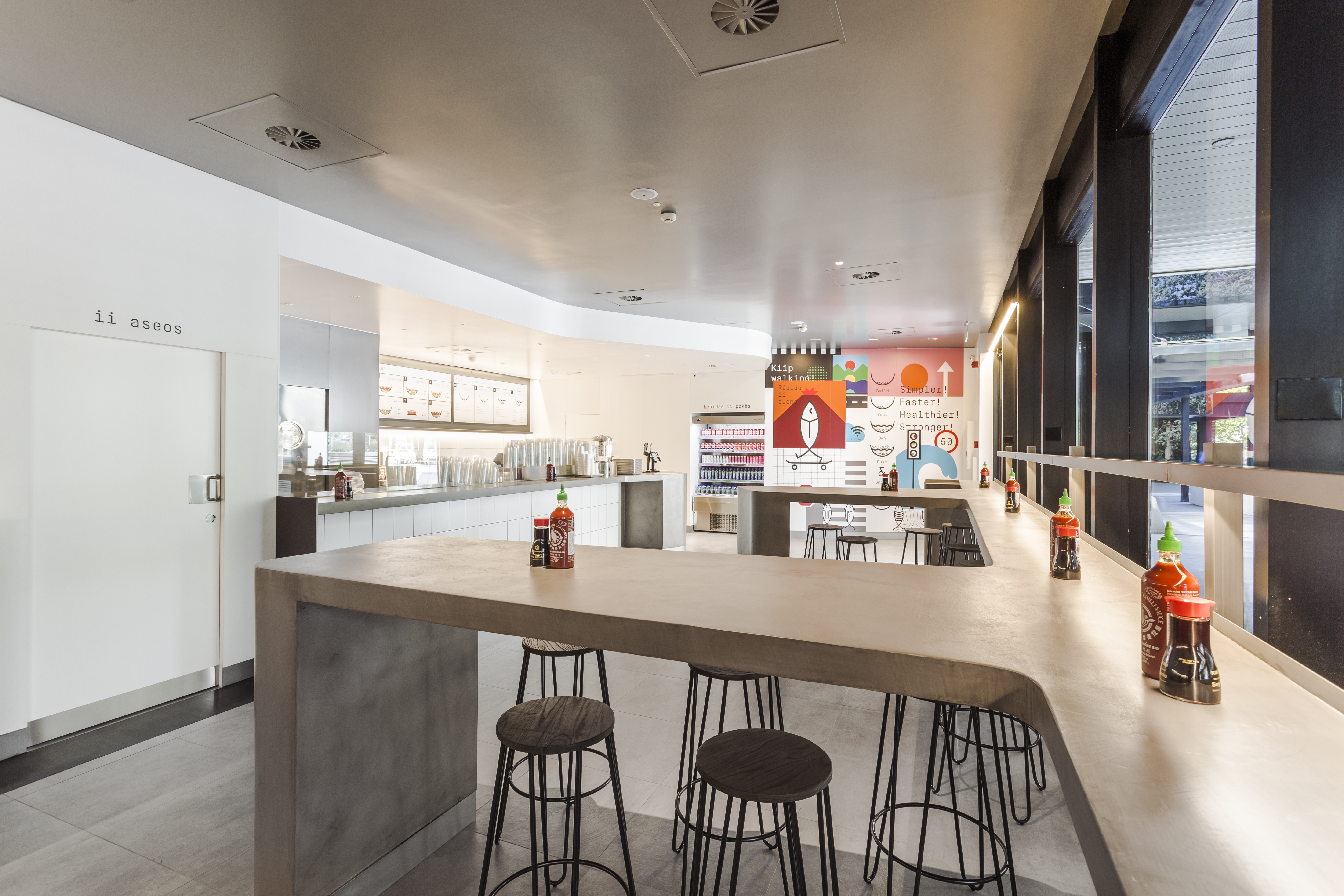 Modern dining area with large-format concrete-look floor tiles and long counter.