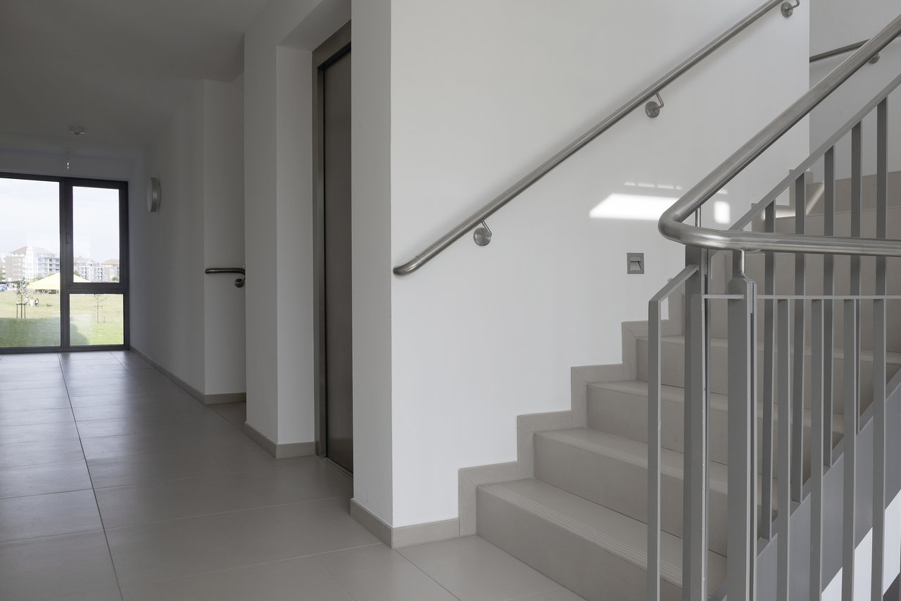 Elegant, large-format light grey tiles for hallway and stairs.