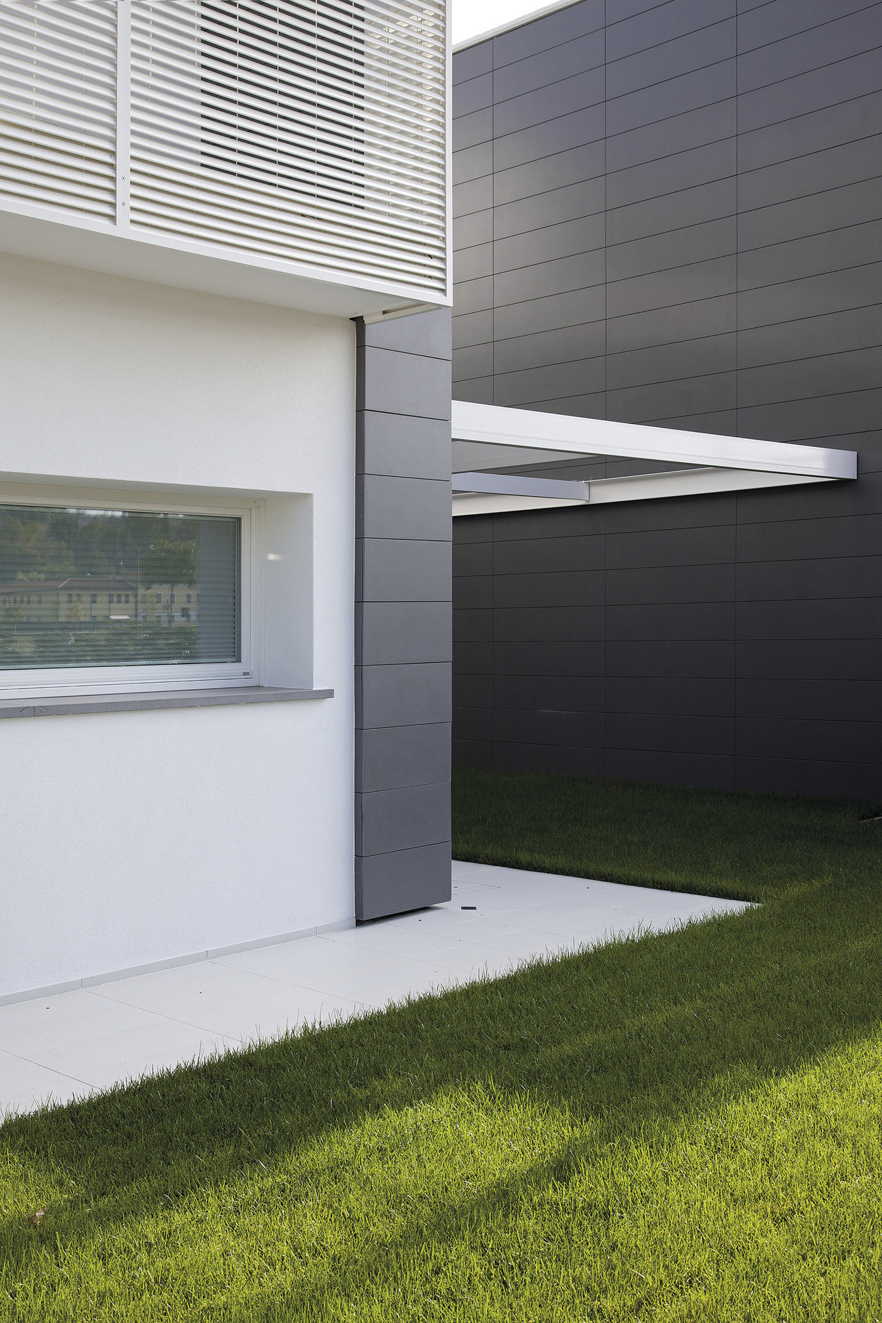 Light outdoor tiles on a modern terrace with lawn.