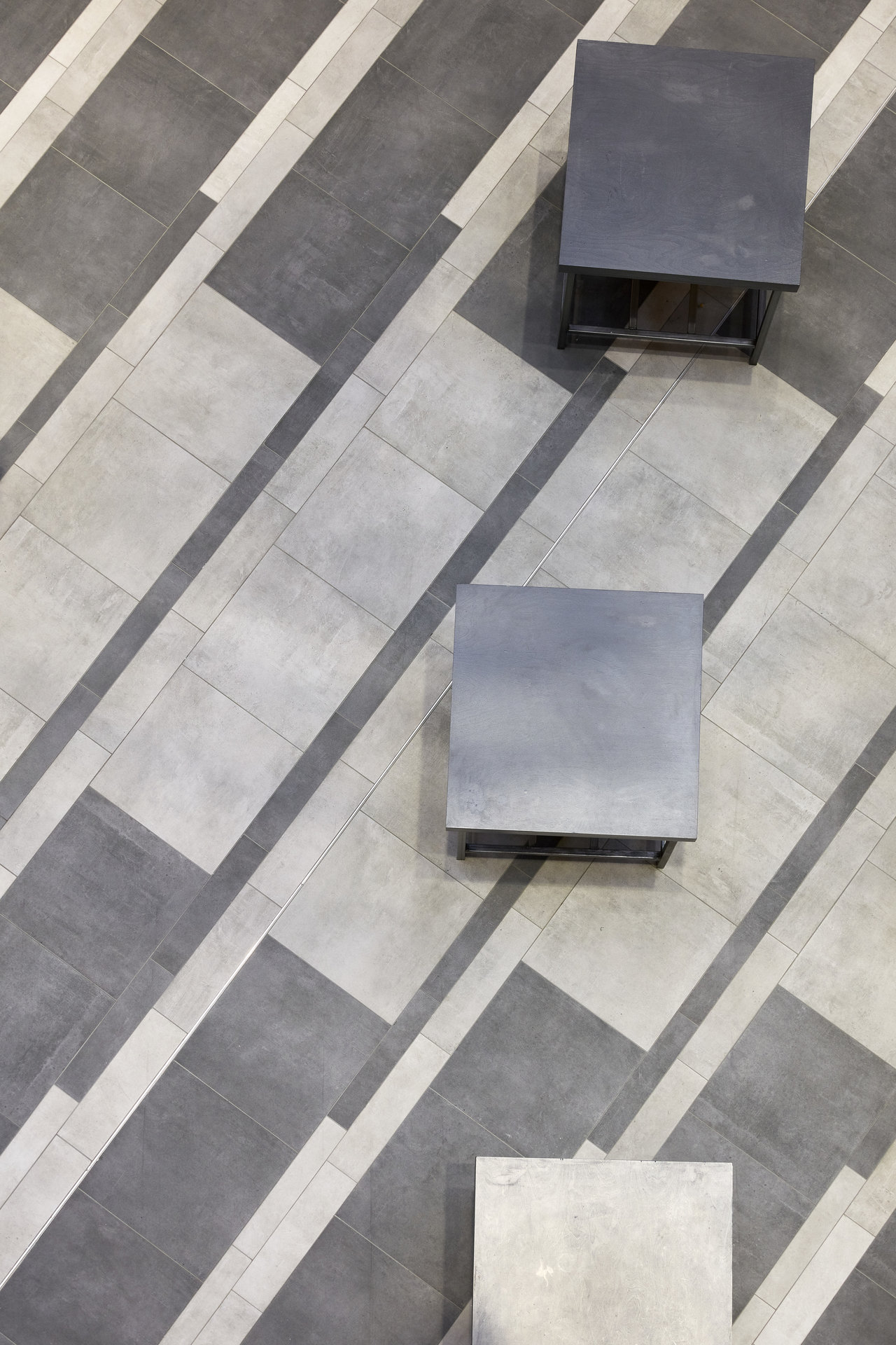 Modern grey and light grey floor tiles with a dynamic diagonal pattern.