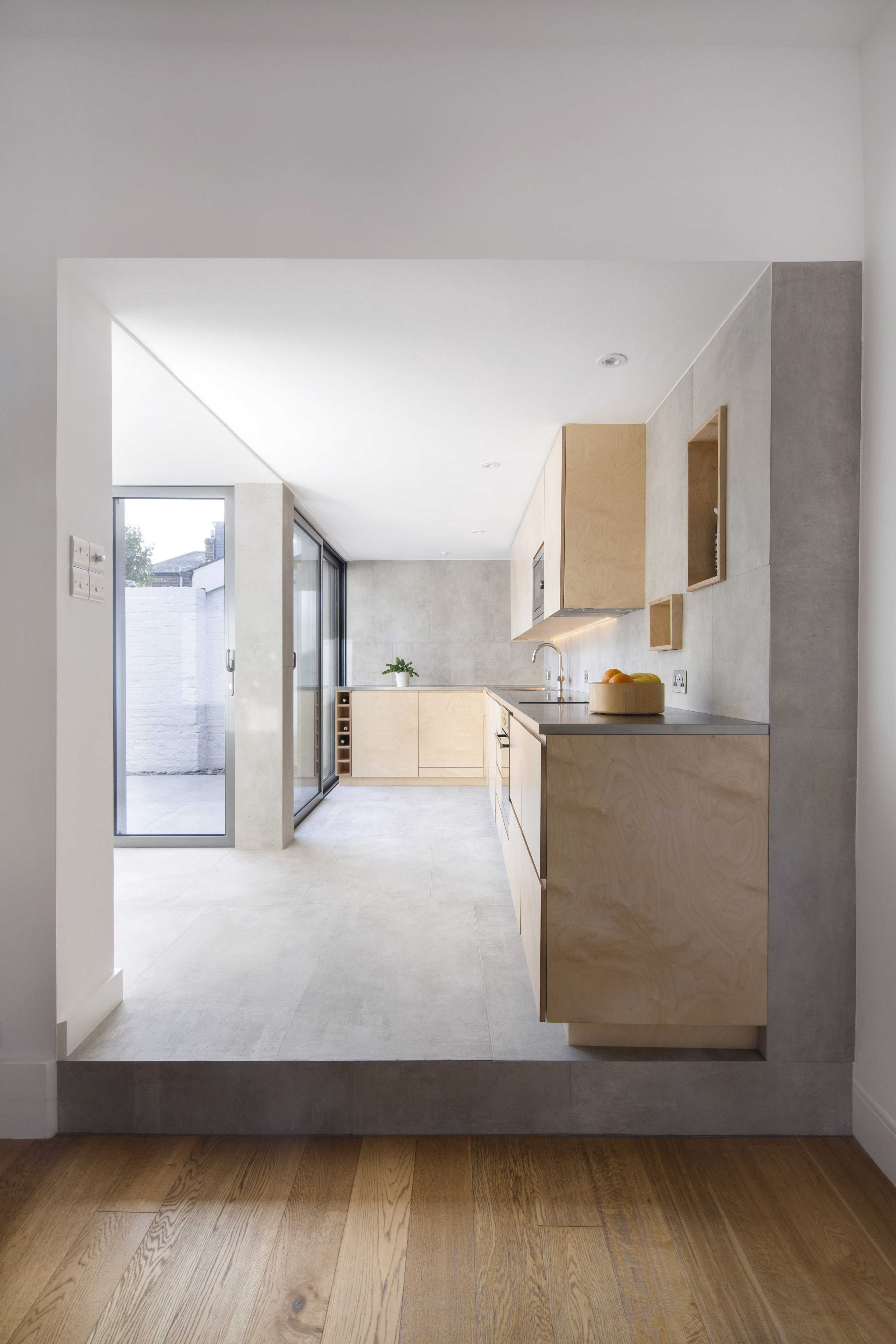 Light concrete-look tiles in a modern kitchen and on the terrace for a seamless transition.