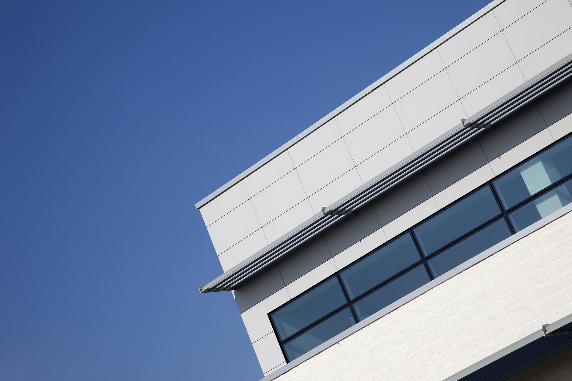 Moderne Architektur mit klaren Linien und großen Fenstern unter blauem Himmel.