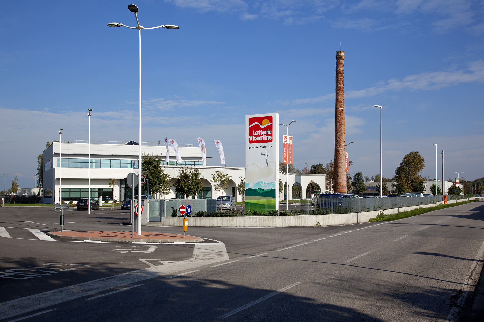 Factory premises with a modern building, a large 'Latterie Vicentine' sign, and a tall brick chimney.