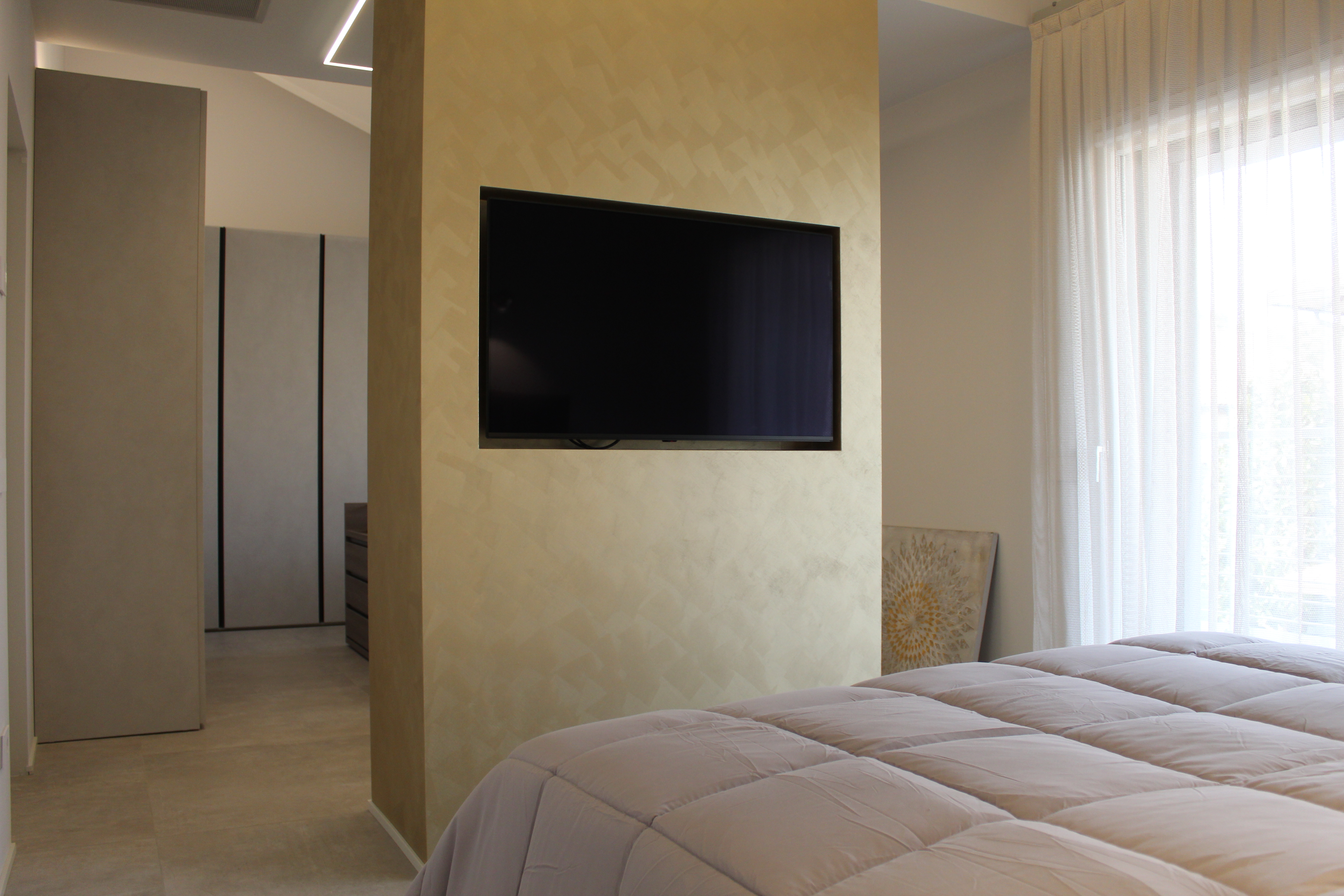 Modern bedroom with TV wall and light, stylish floor tiles.