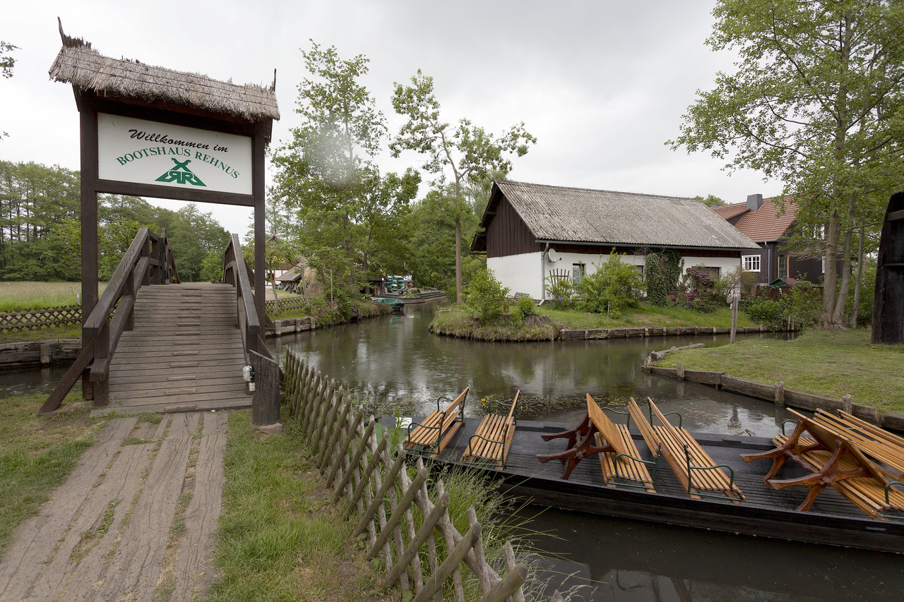 Boathouse Rehna with a wooden bridge over a canal and benches on a boat.