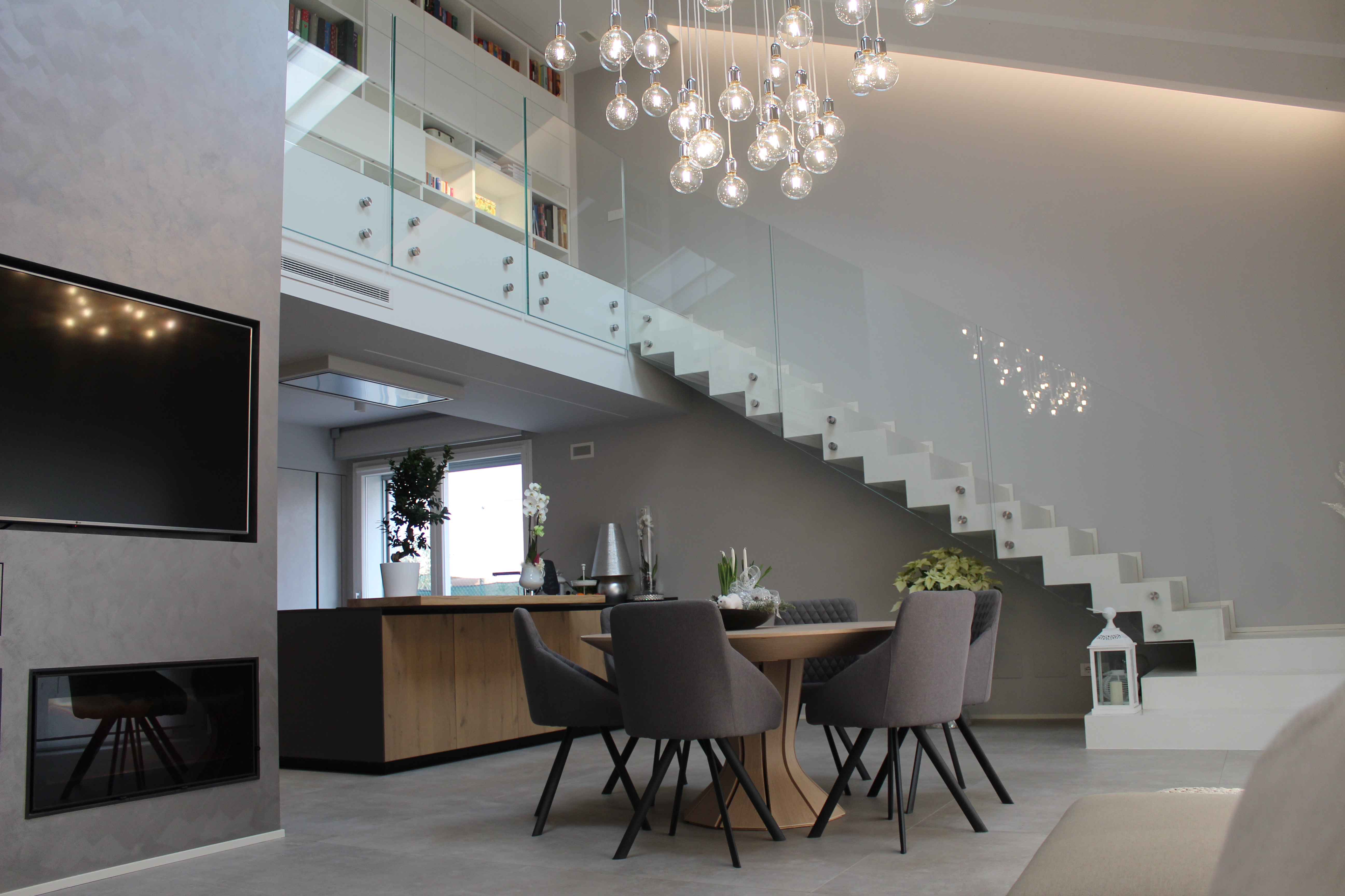 Modern living area with large-format grey tiles, dining area, and open gallery.