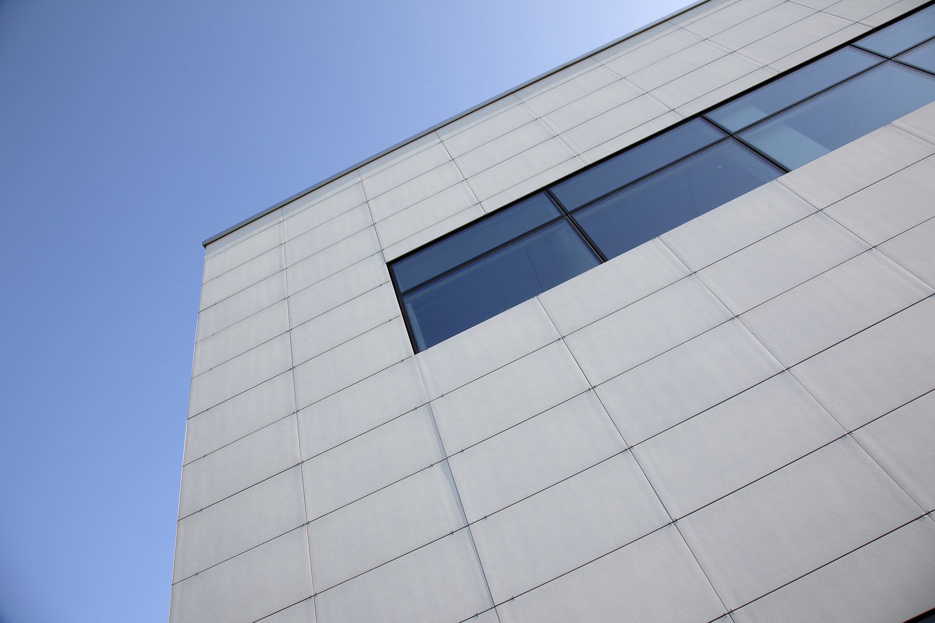 Large-format, light-coloured tiles on a modern building facade.