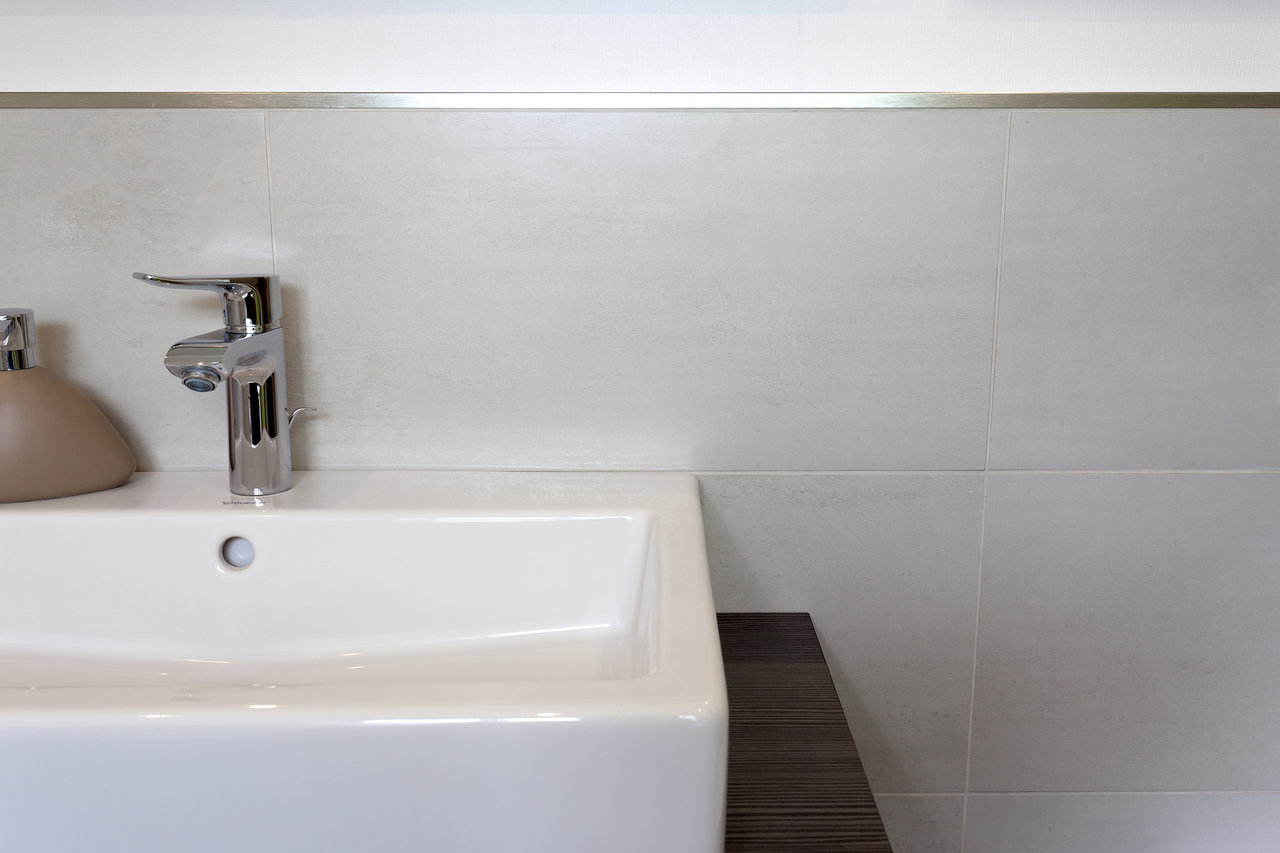 Bright, modern bathroom wall tiles with sink and tap.