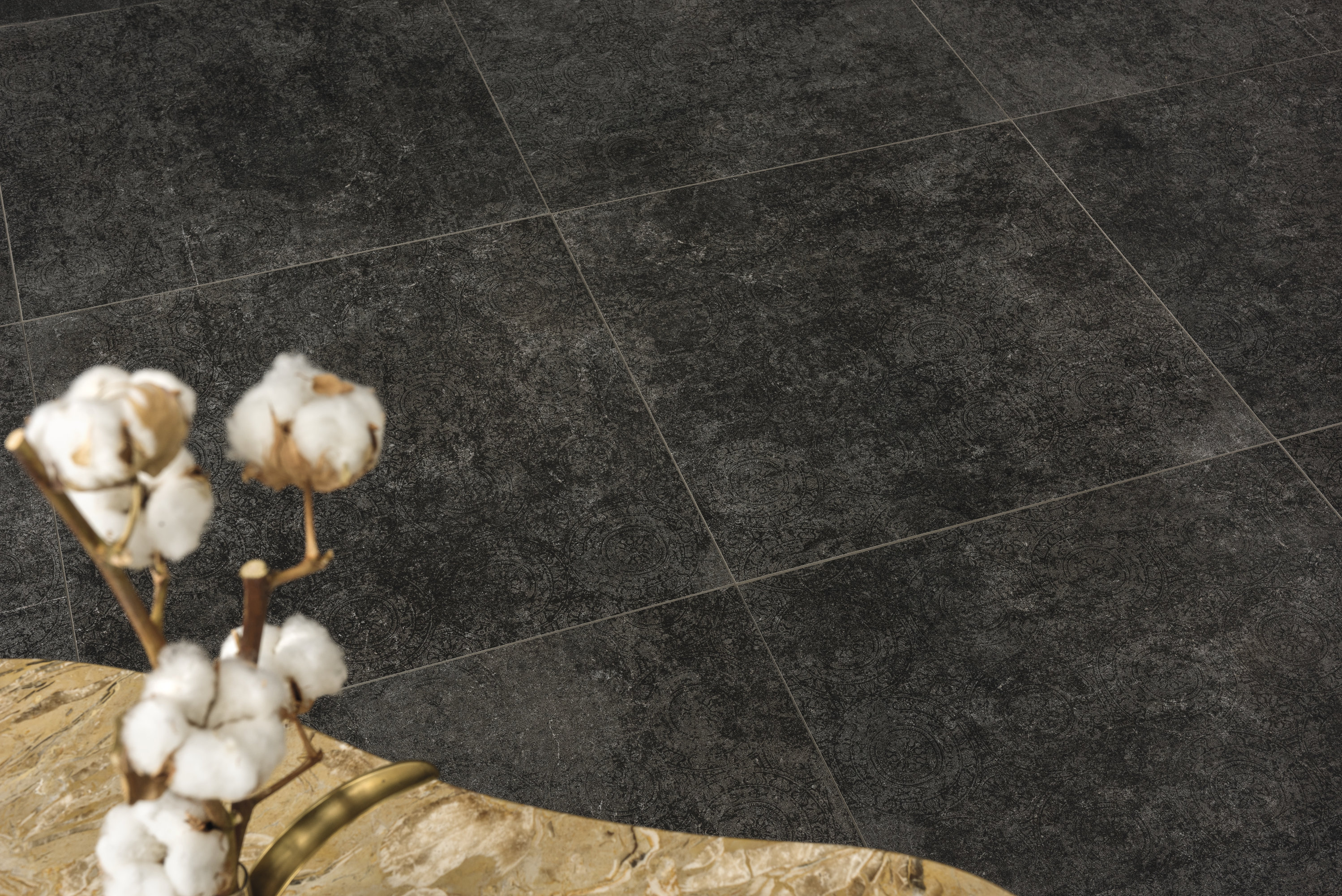 Textured anthracite tiles with cotton branch.