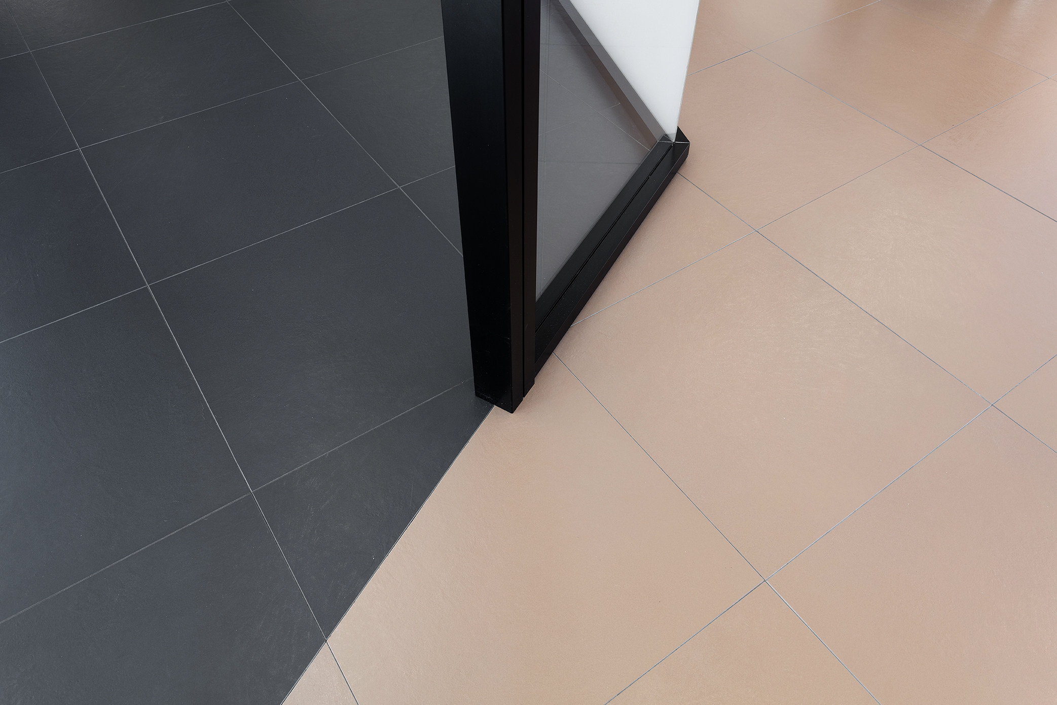 Stylish tile floor: Contrasting anthracite & beige, divided by a door frame.