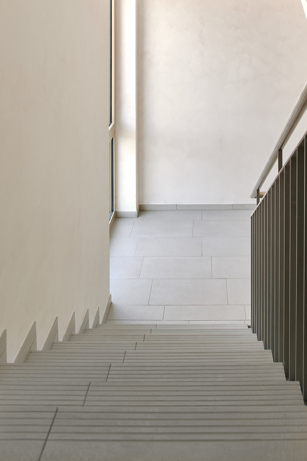 Modern staircase and landing with light grey tiles.