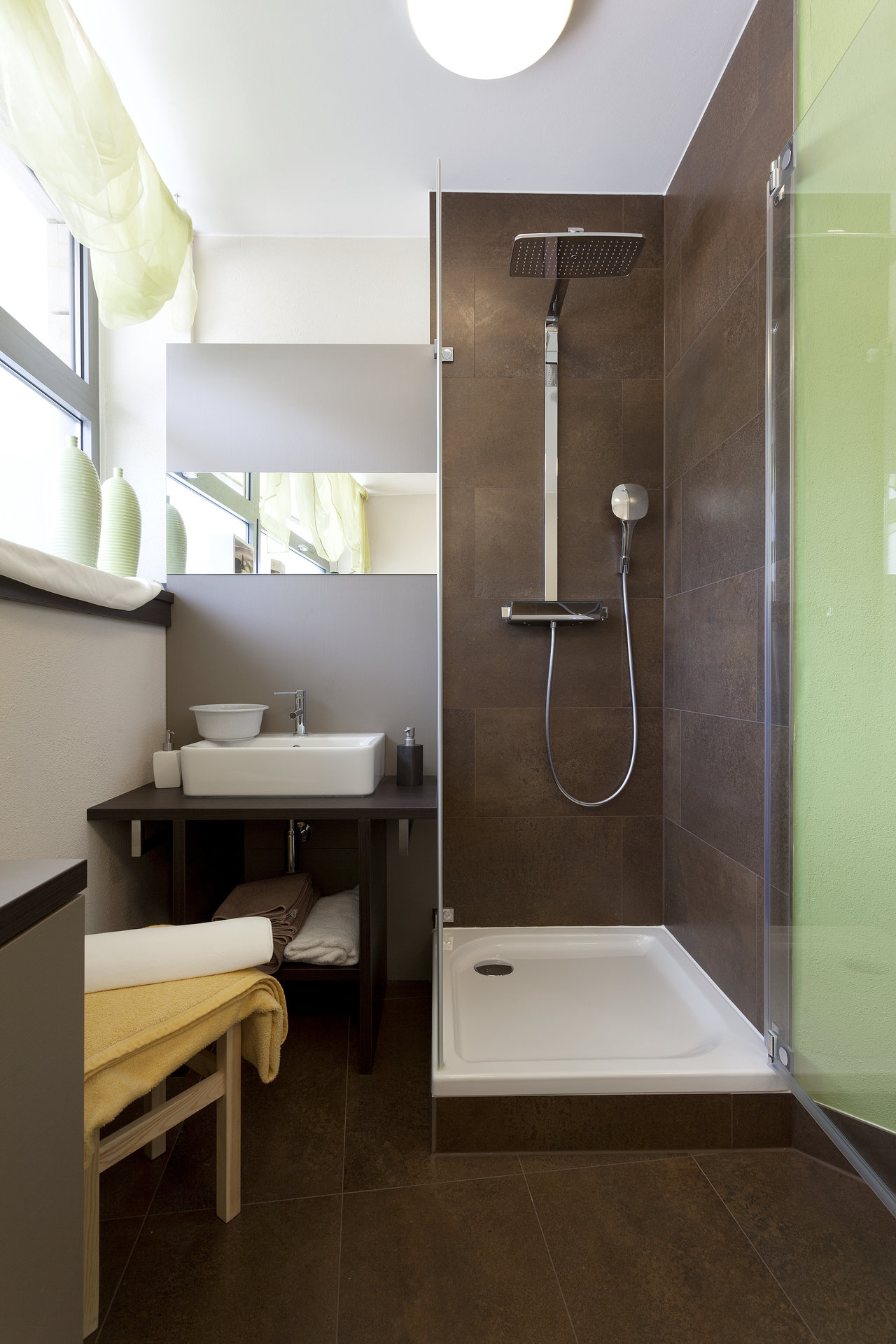 High-quality brown floor and wall tiles in a modern bathroom with a shower.