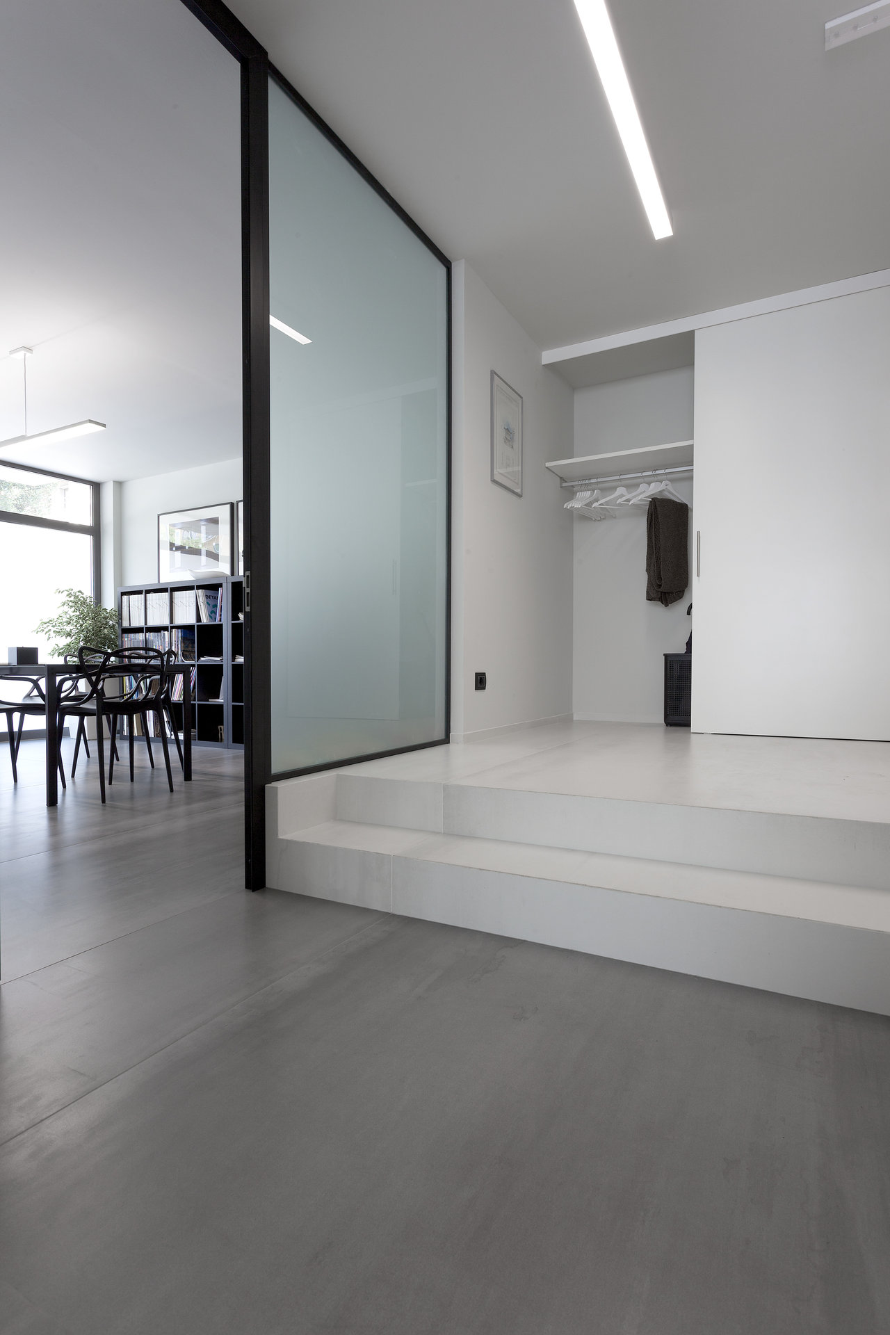 Modern interior with dark and light tiles on two levels, separated by glass.