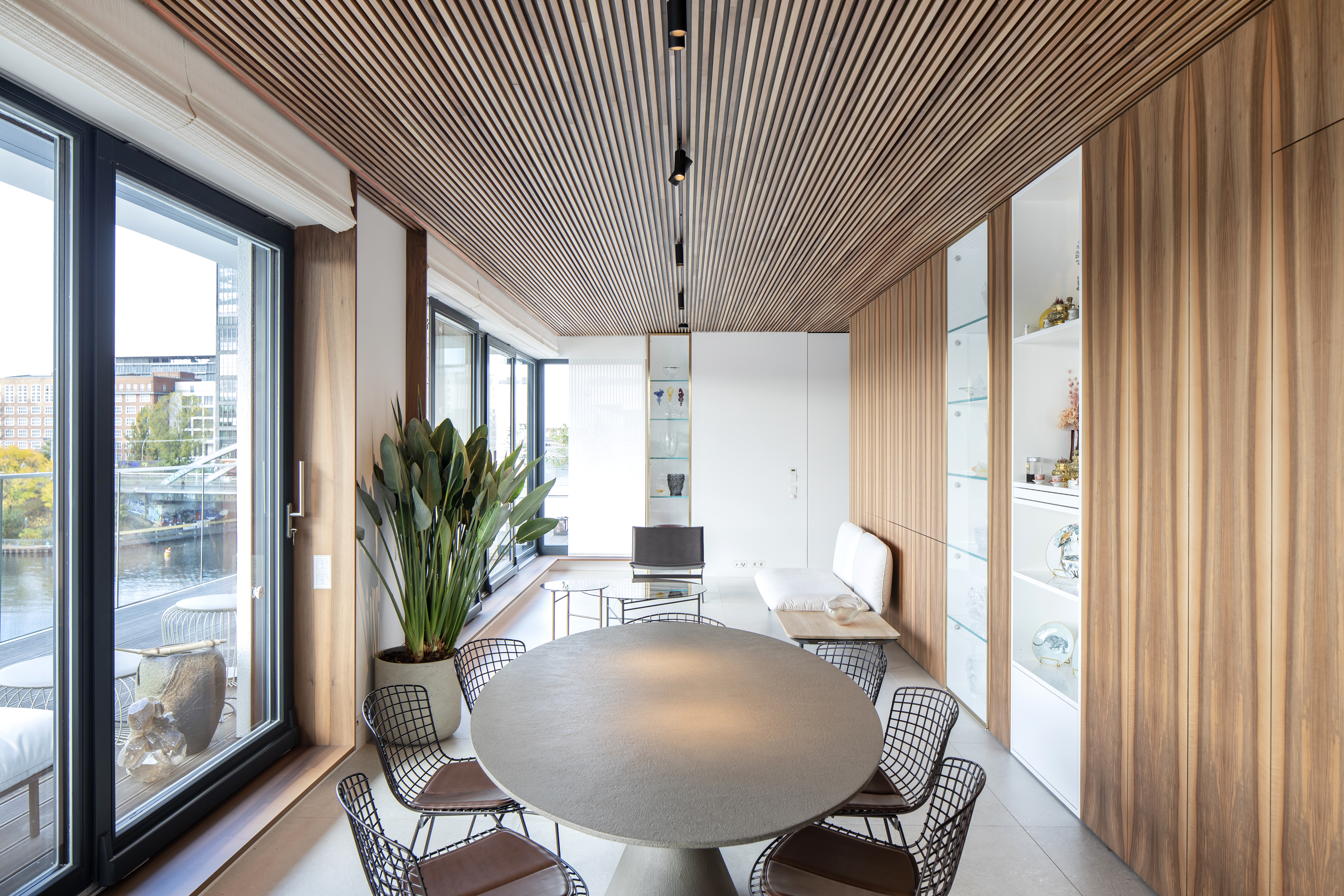 Modern dining room with light floor tiles, wooden walls, and river view.