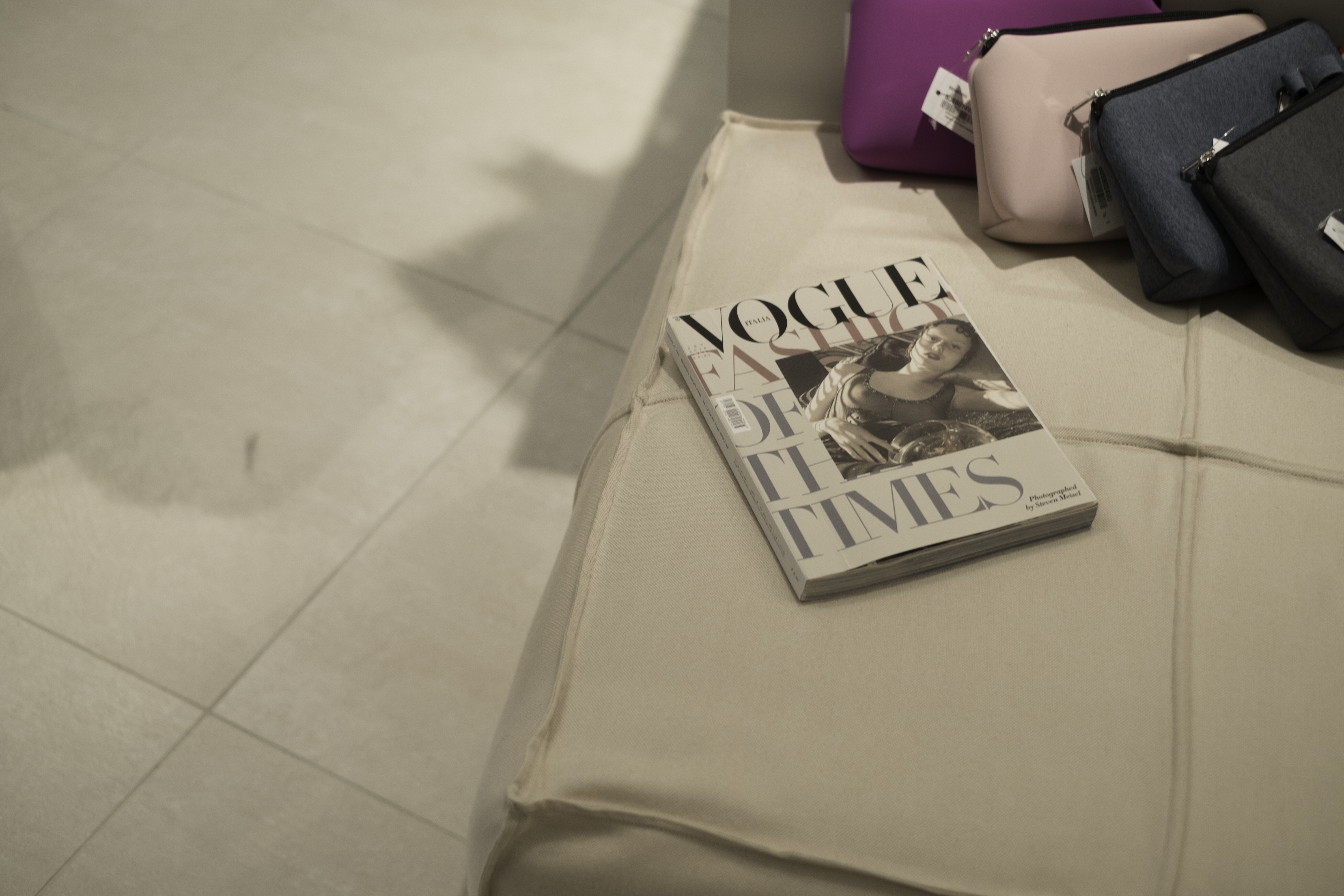 Bright, large-format tiles in a modern living room with a couch and magazine.
