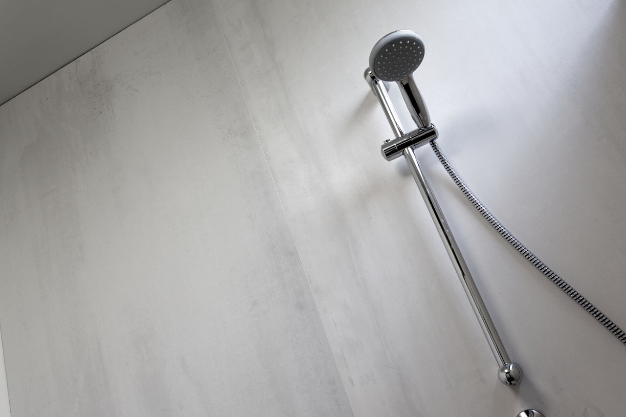 Modern shower fitting on a light grey wall with concrete-effect tiles.
