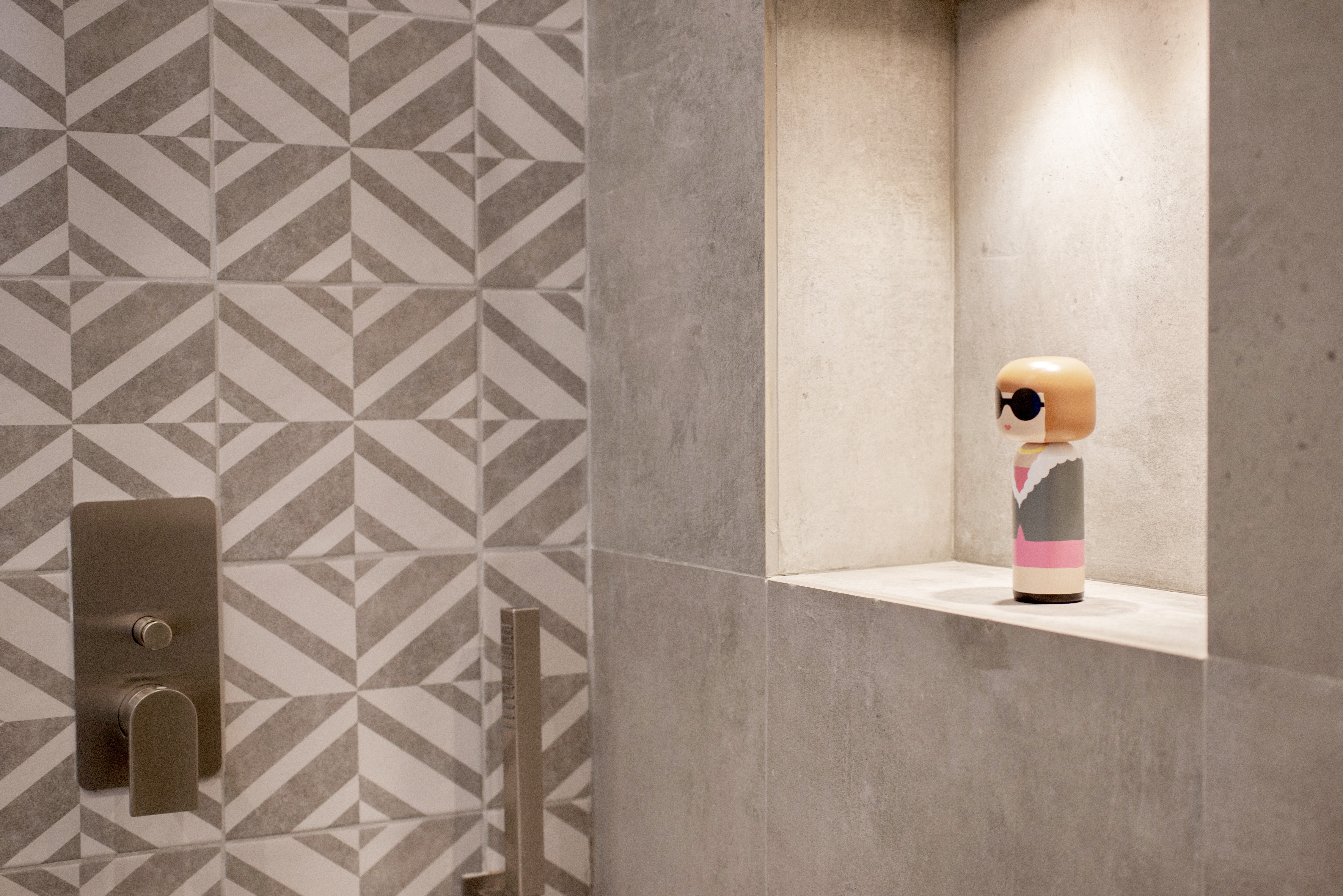 Modern shower design with high-quality patterned and grey tiles, including an illuminated storage niche.