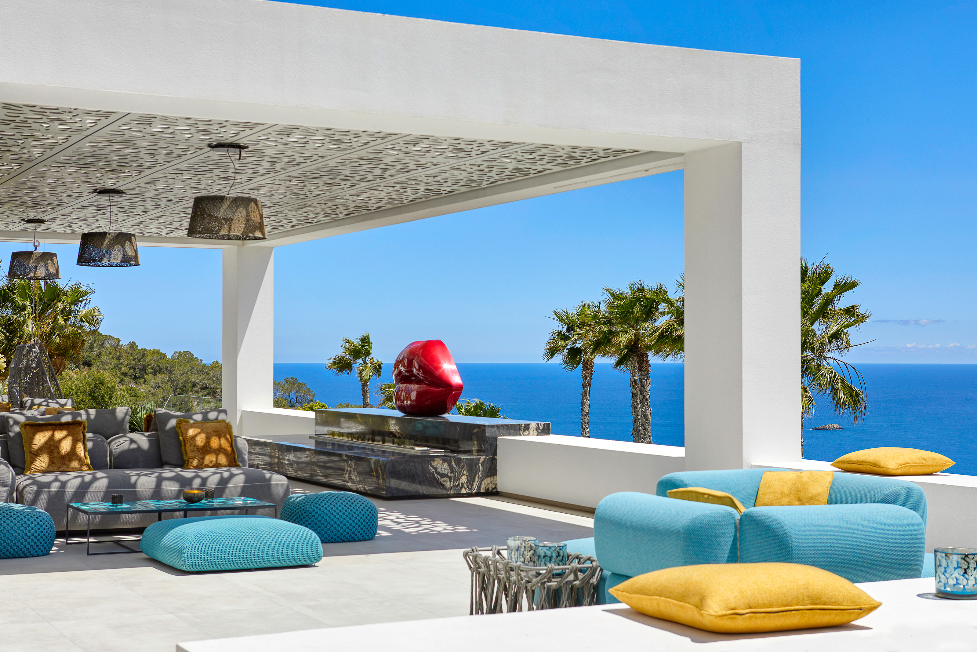 Modern outdoor lounge on tiled terrace with sea view.