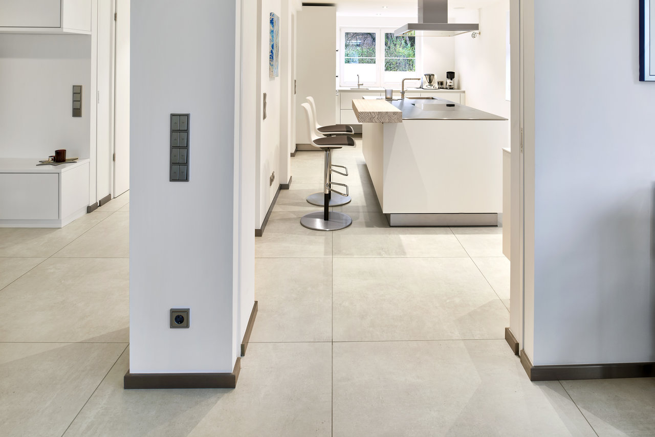 Light, large-format tiles create an open, modern ambiance from hallway to kitchen.