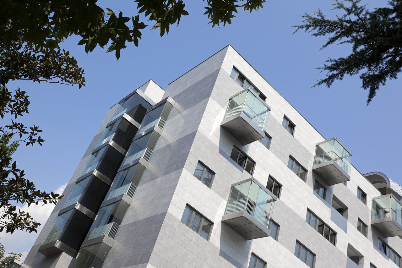 Modern facade with grey outdoor tiles and glass balconies.