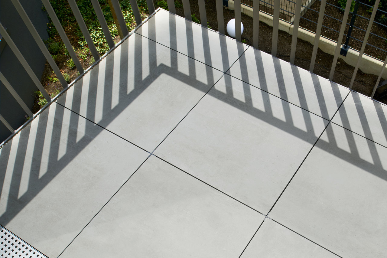 Light grey premium outdoor tiles on a modern terrace with shade.