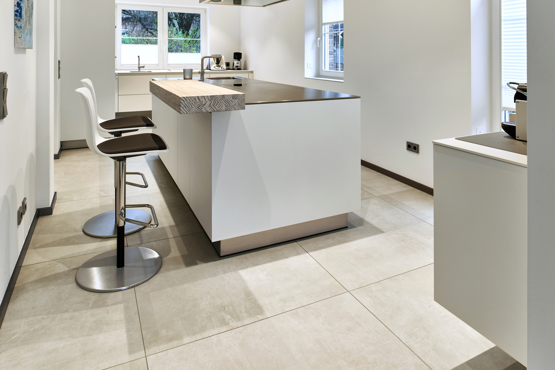 Light, large-format floor tiles in a modern kitchen with an island.