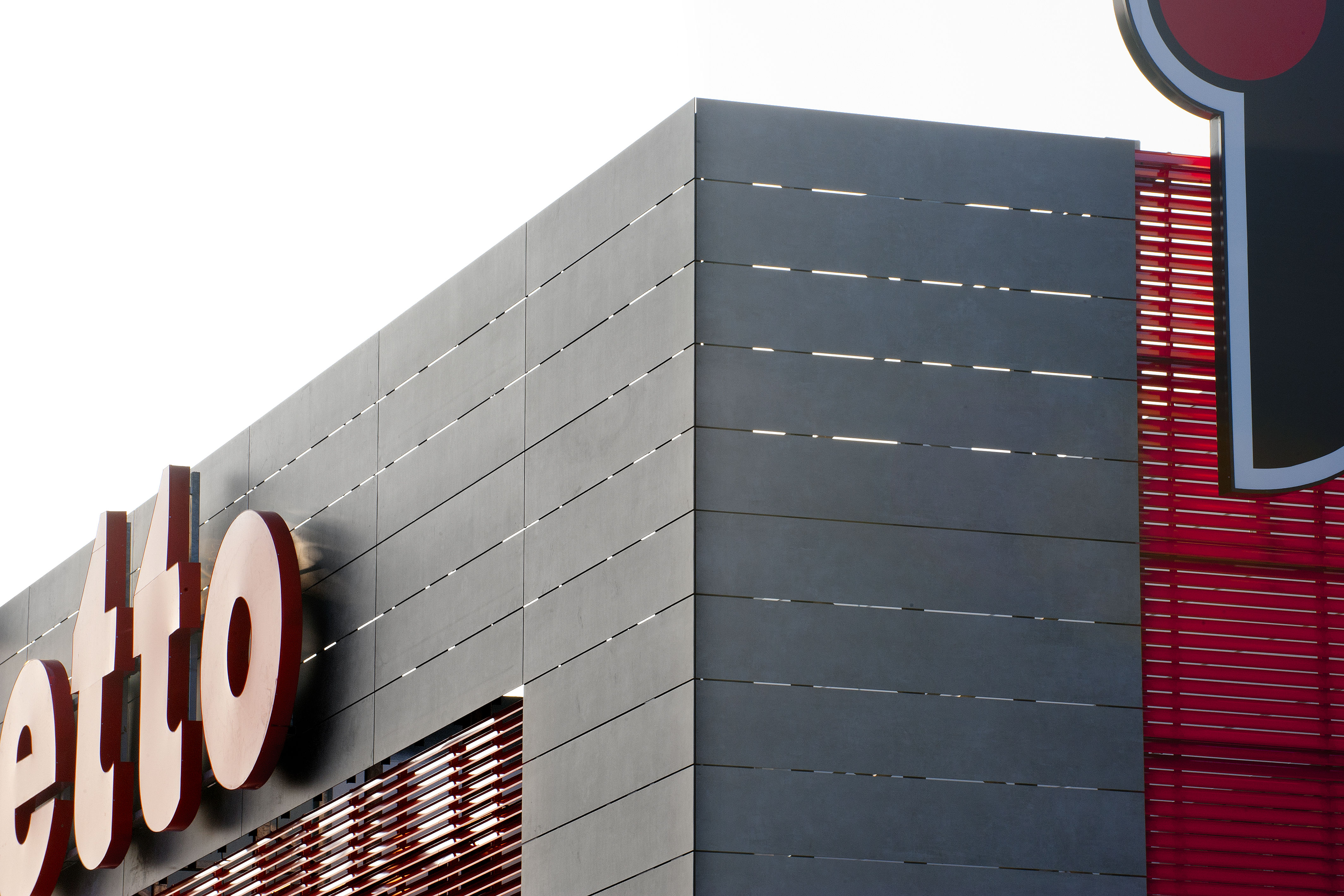 Modern facade with dark grey large-format tiles and red accents.