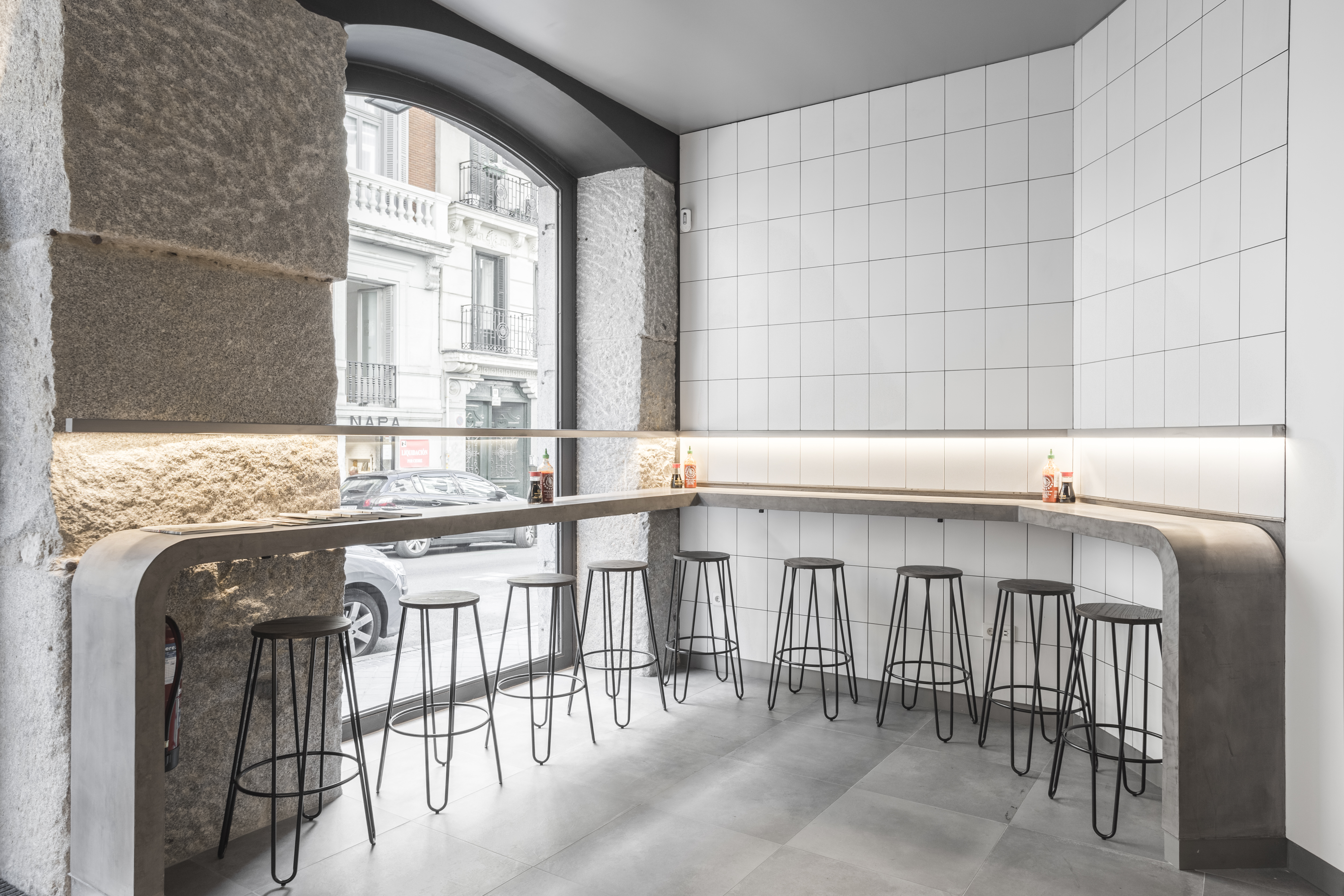 Minimalist interior with white wall and grey large-format floor tiles.