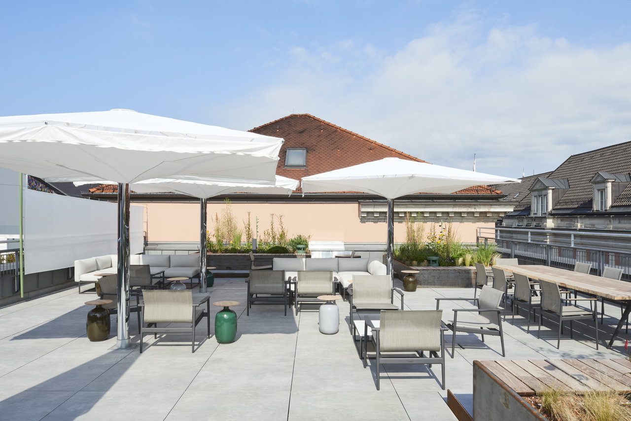 Bright, modern rooftop terrace with high-quality outdoor tiles, lounge furniture, and parasols.