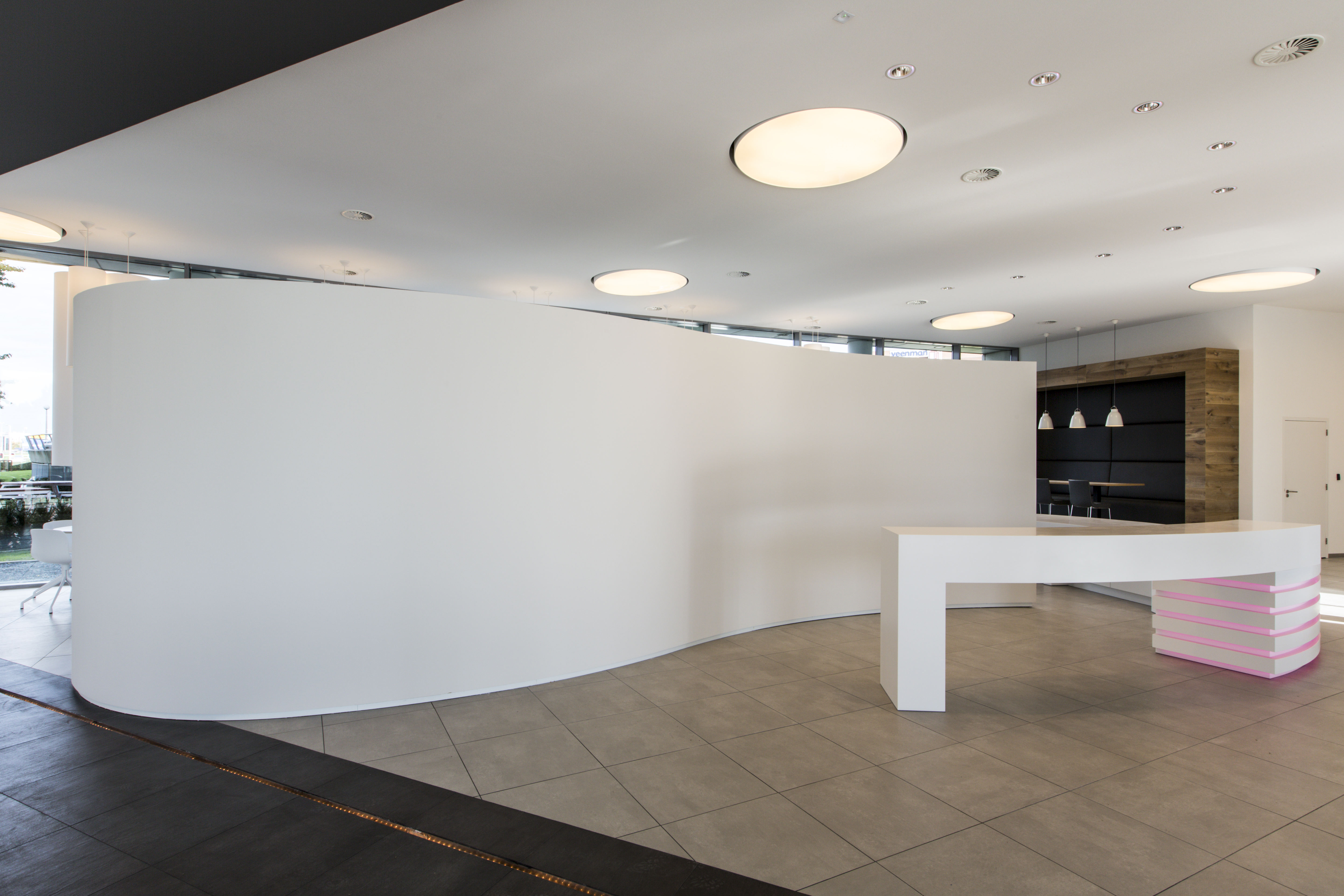 Modern reception area with light floor tiles and a curved design wall.