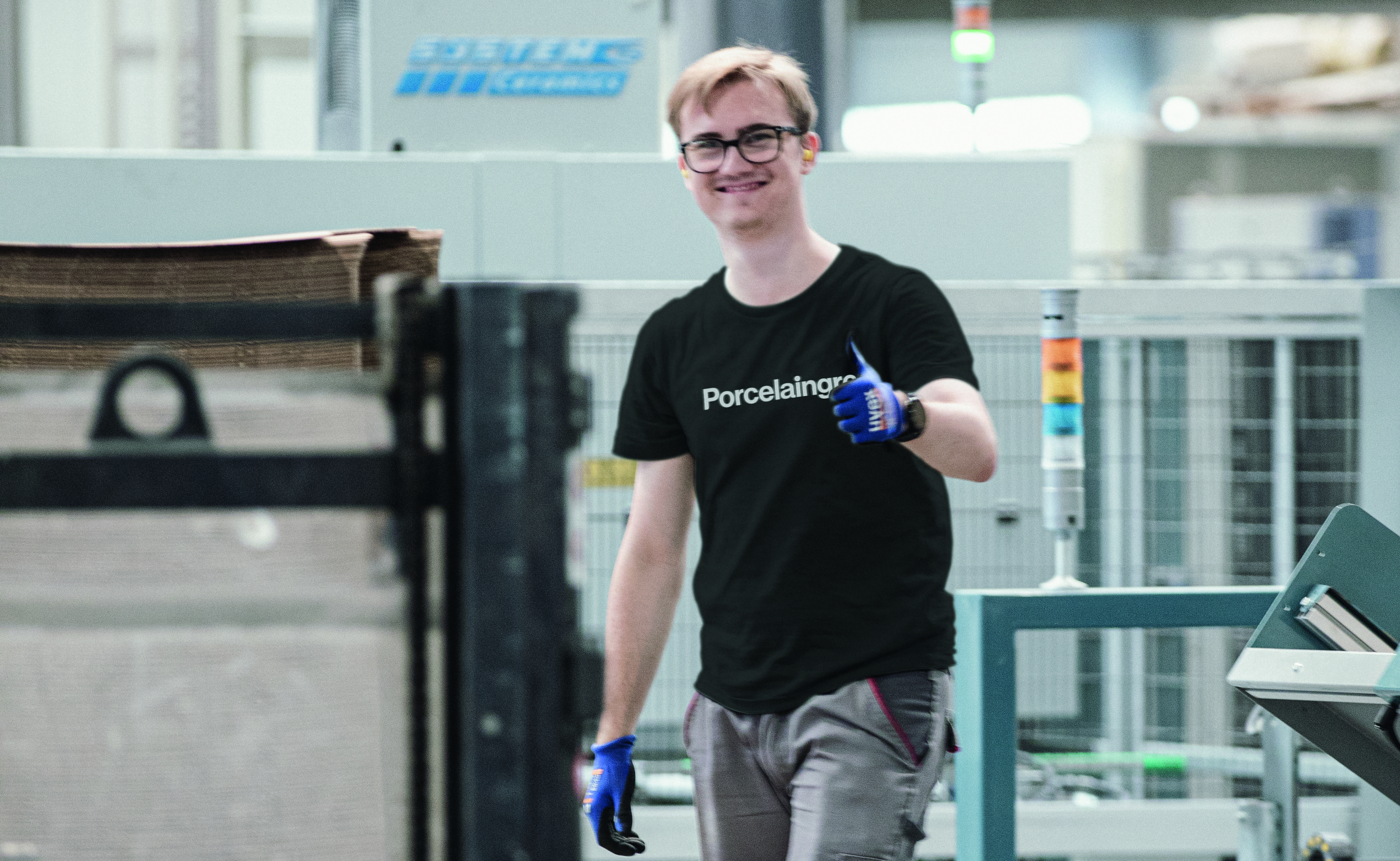 A smiling Porcelaingres employee in tile production gives a thumbs up.