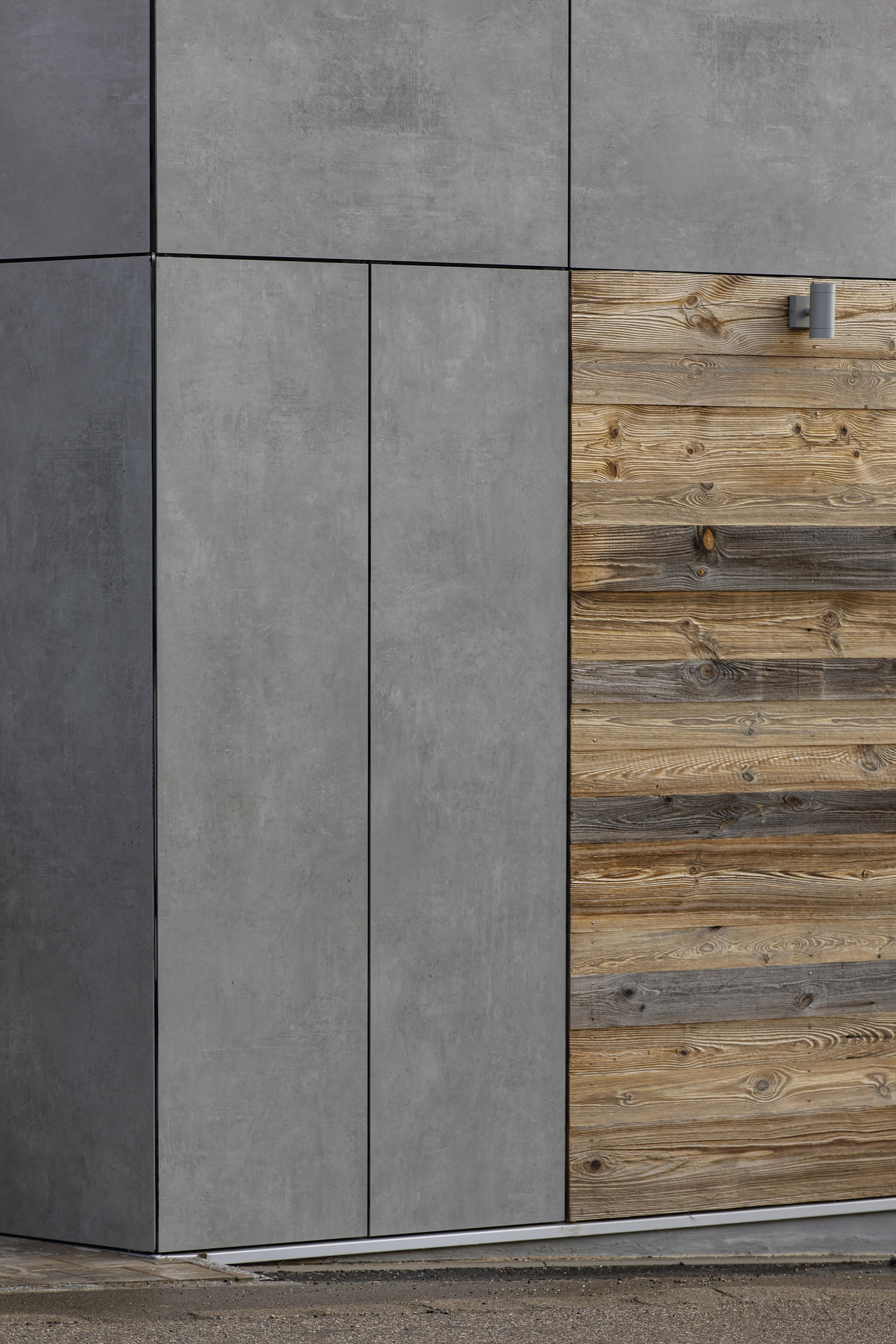 Modern exterior wall with grey concrete-look tiles and rustic wooden panels.