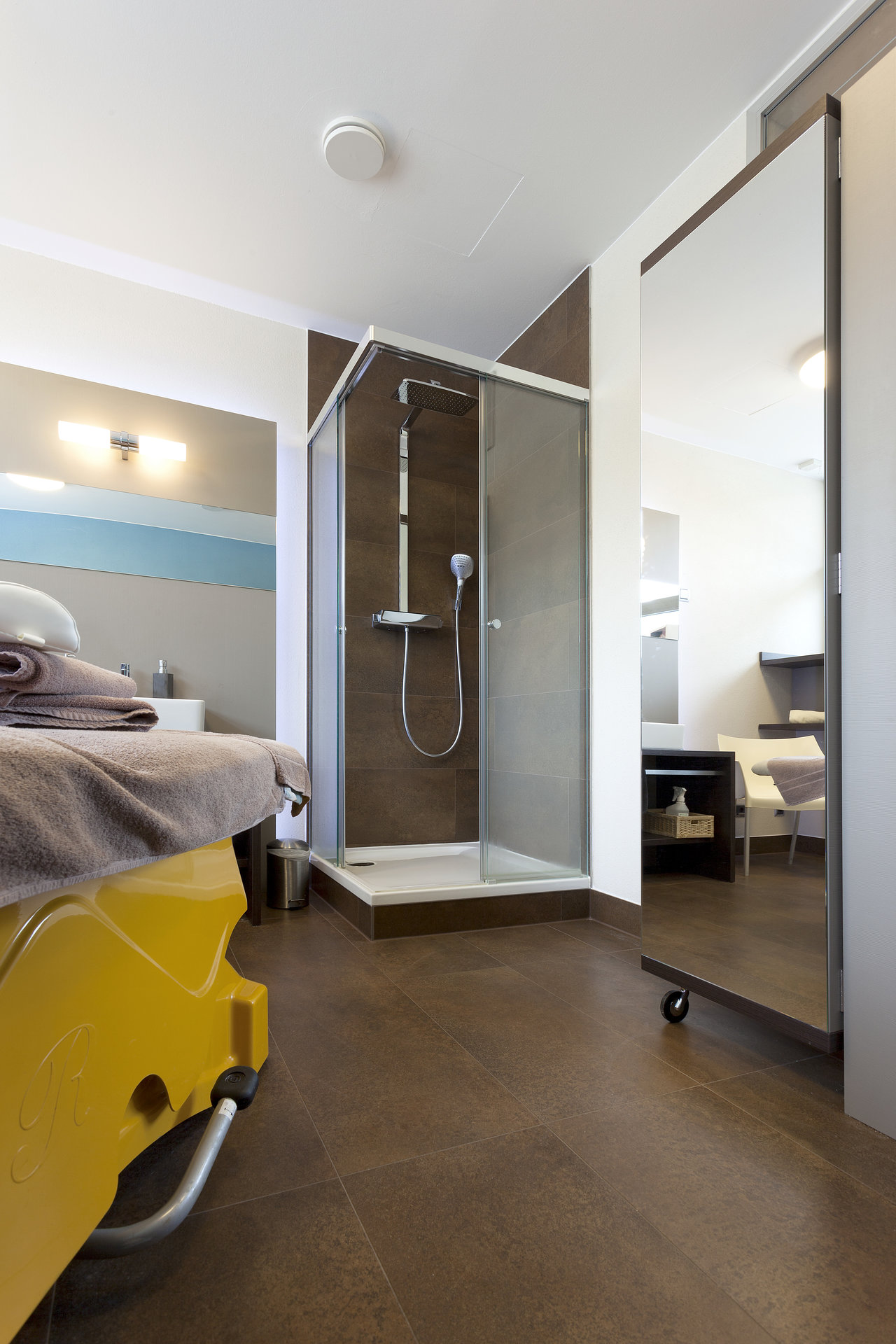 Dark brown floor and wall tiles in a stylish bathroom with a shower.