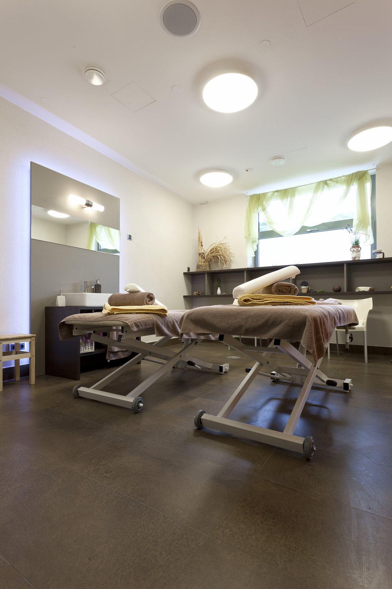 Dark large-format tiles in a modern spa with massage beds.